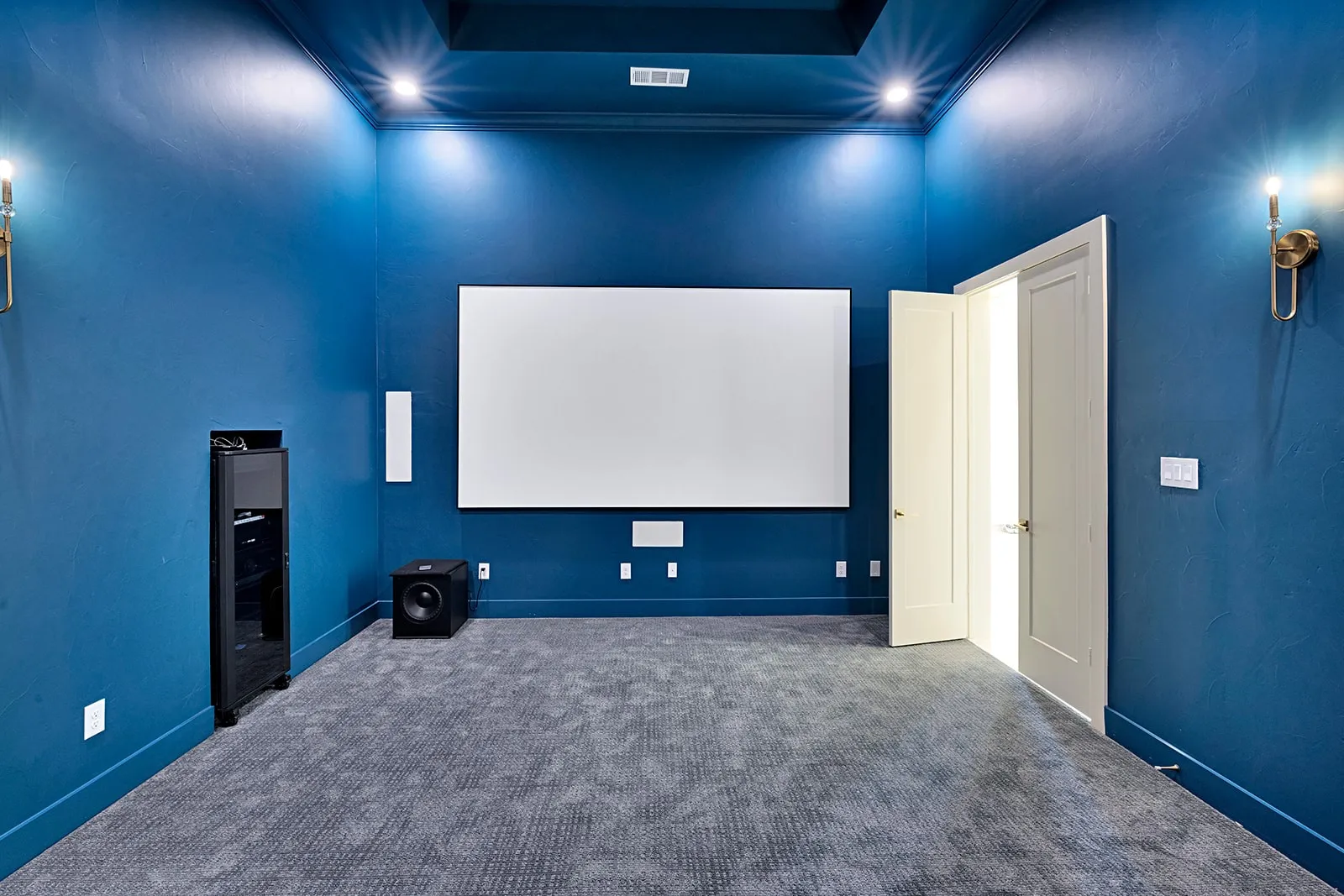 Dedicated media room featuring a large projection screen, recessed ceiling lighting, and a dark blue accent wall