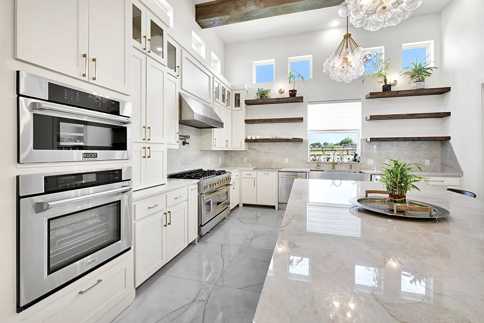 Gourmet kitchen featuring a large central island, white cabinetry, integrated stainless steel appliances, a professional-grade range with a stainless steel hood, and a deep basin sink