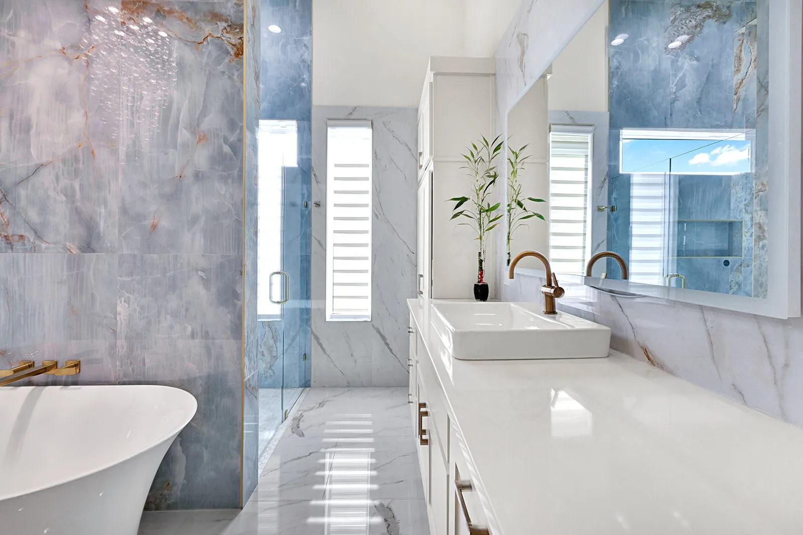 Bathroom featuring a freestanding soaking tub with wall-mounted brass fixtures, a glass-enclosed shower, and a vanity with a rectangular vessel sink and brass faucet