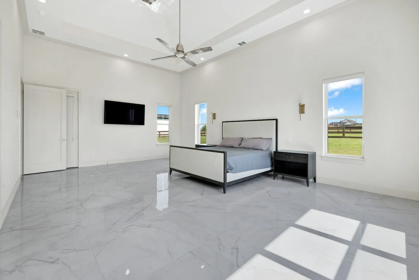 Spacious room featuring vaulted ceilings, recessed lighting, and large format marble-look tile flooring