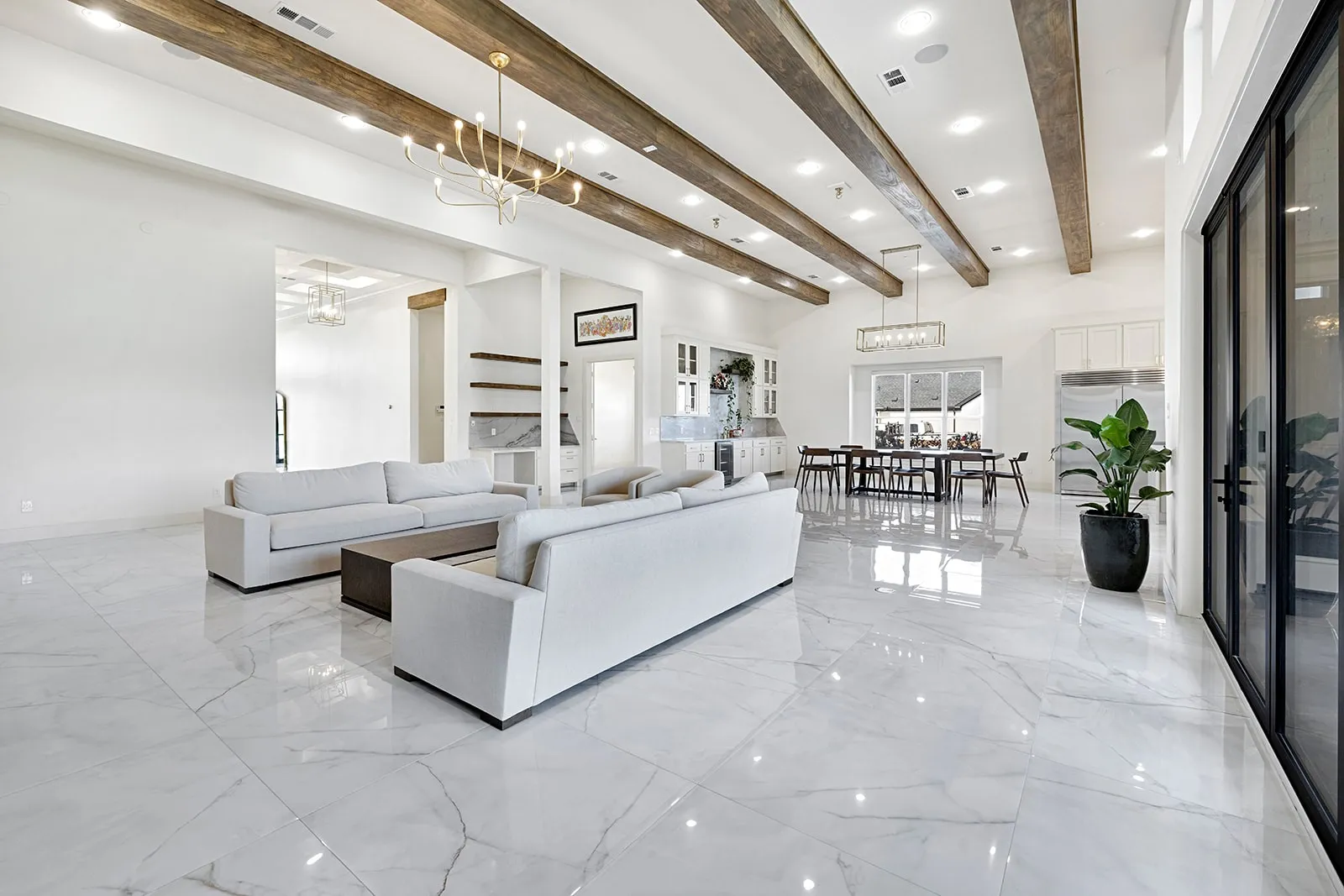 Spacious living area featuring high vaulted ceilings with exposed wood beams, polished marble-look tile flooring, and recessed lighting