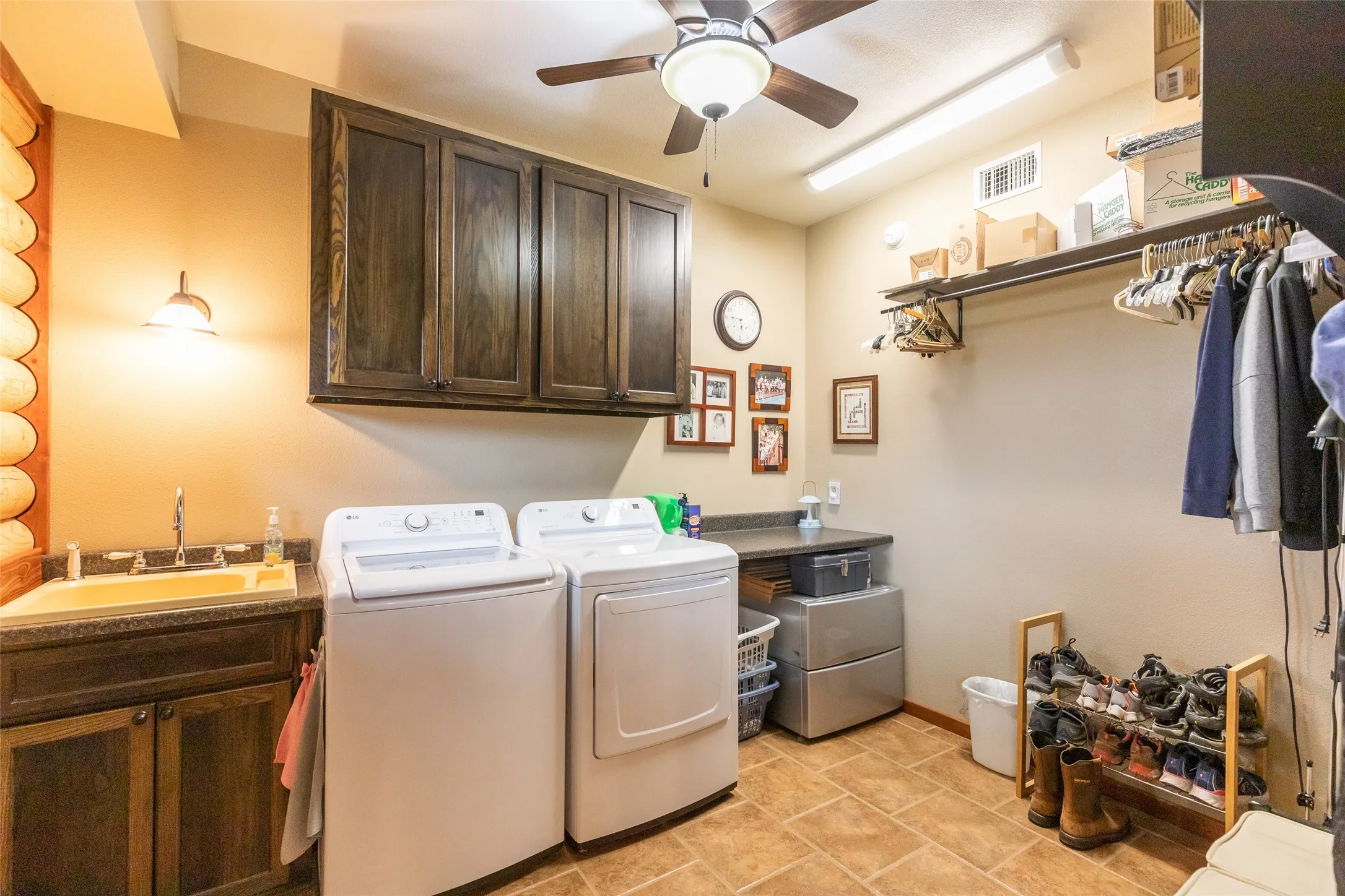 Large laundry room with a sink, storage space, and room for hanging wet clothes and drying off footwear.