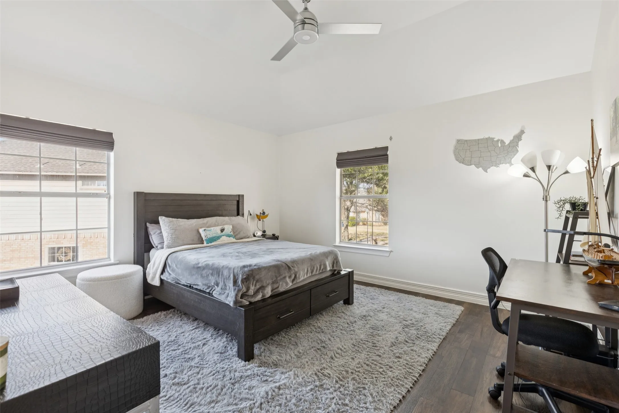 Spacious room featuring vaulted ceilings, dark wood-finish flooring, and two large windows with dark blinds