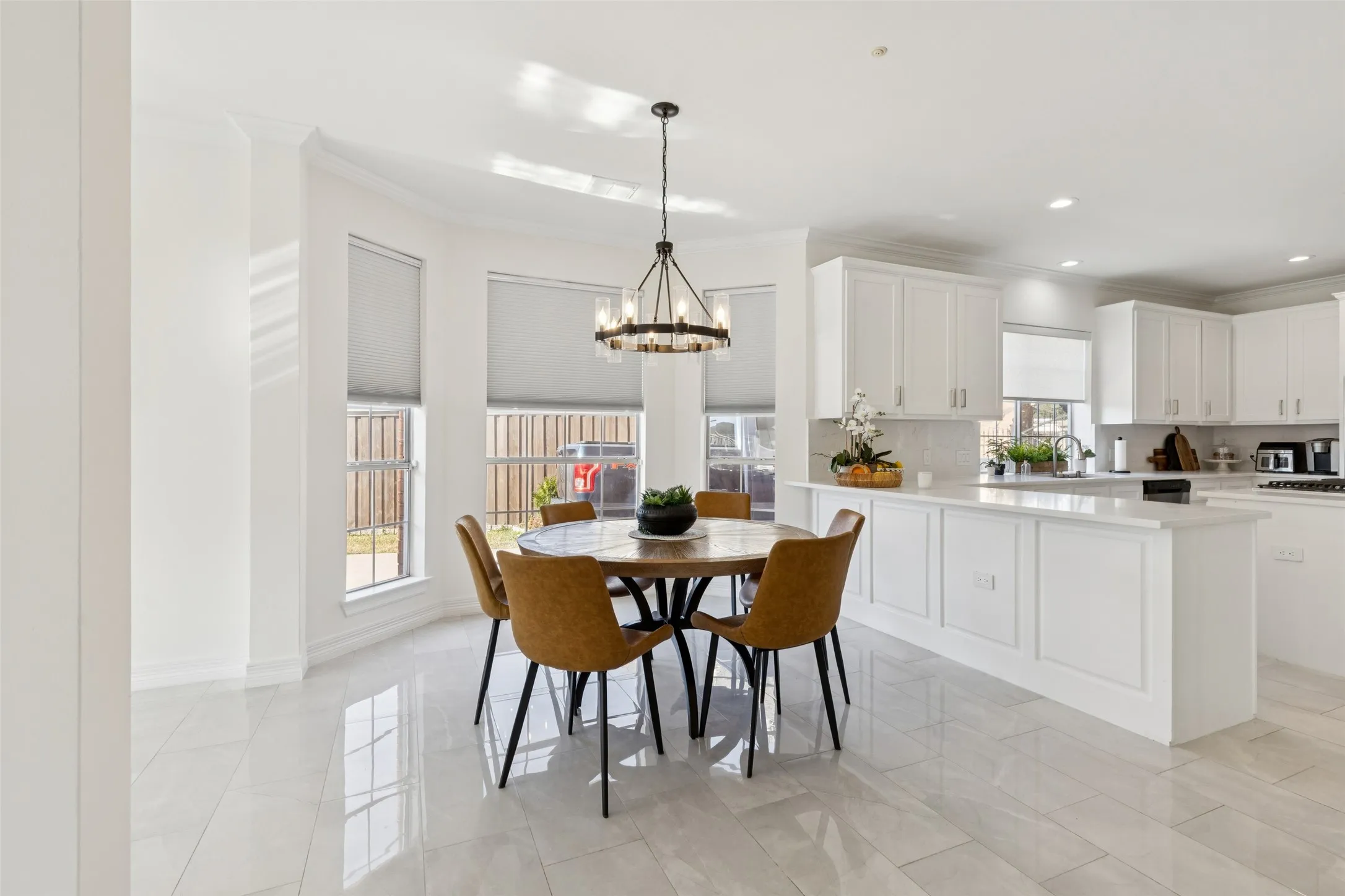 Dining area with bay windows featuring roller shades, an overhead chandelier, and light-toned tile flooring