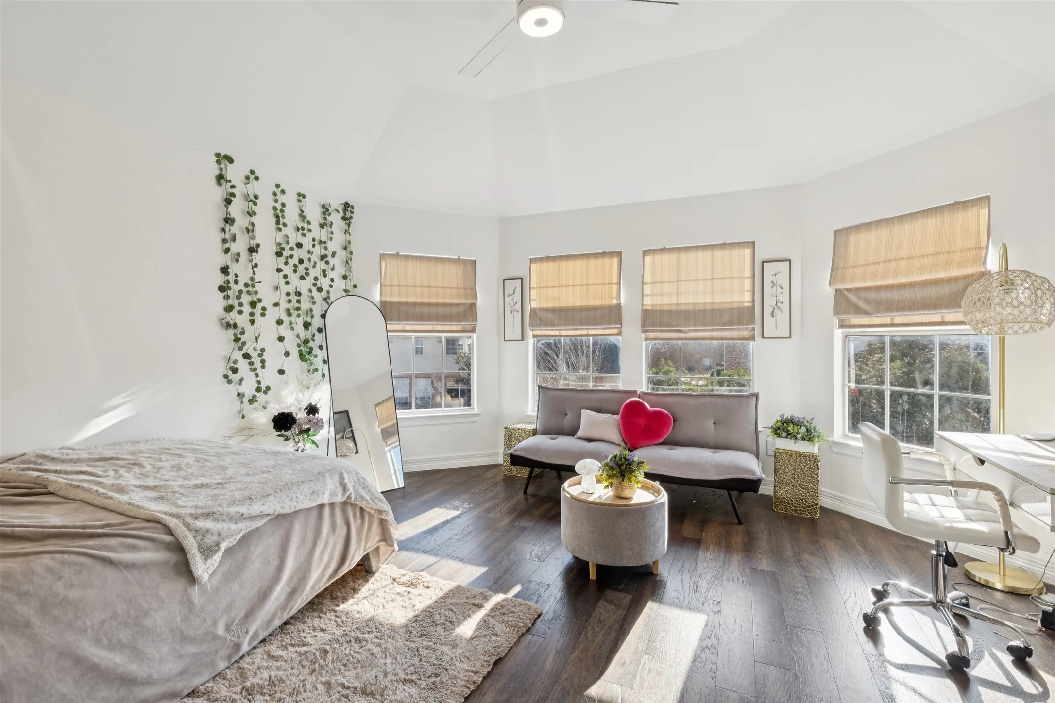 Bright room featuring high vaulted ceilings, dark wood-finish flooring, and multiple windows with installed window treatments