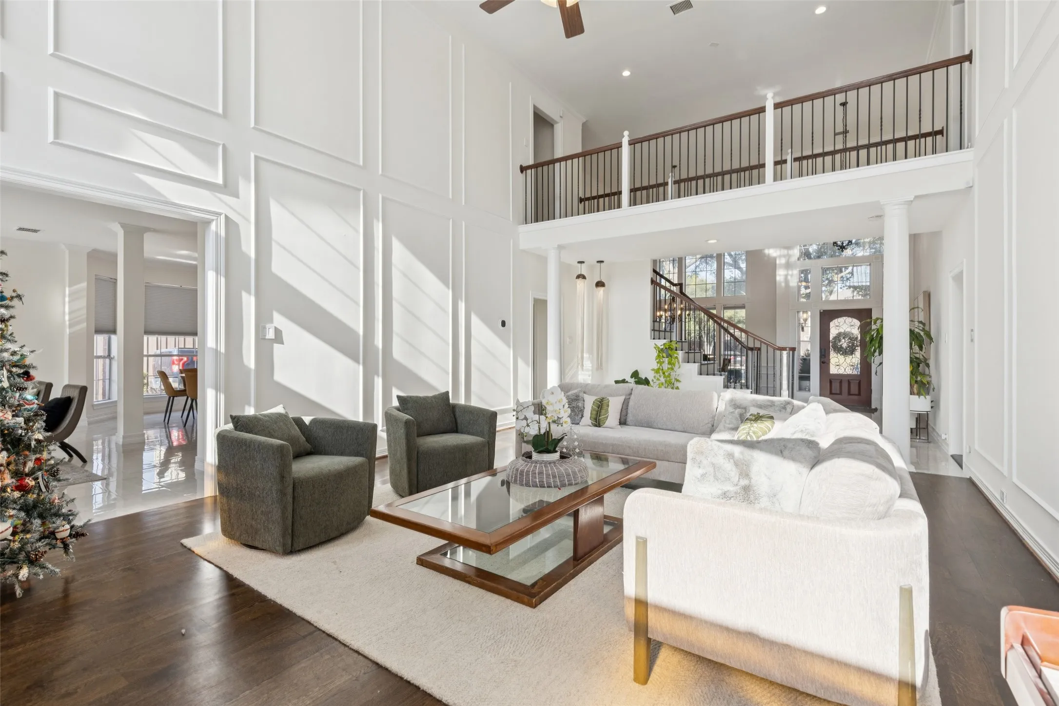 Two-story living area featuring dark wood-finish flooring, white paneled walls, and an open balcony overlooking the space
