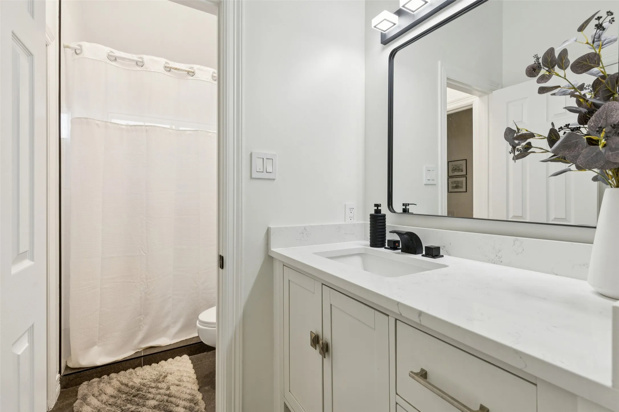 Bathroom featuring a white vanity with integrated sink, a large framed mirror, and matte black fixtures