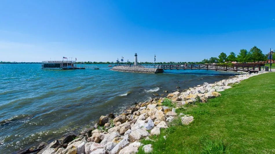 Waterfront setting featuring a wooden pedestrian bridge, a lighthouse structure, and a floating dock