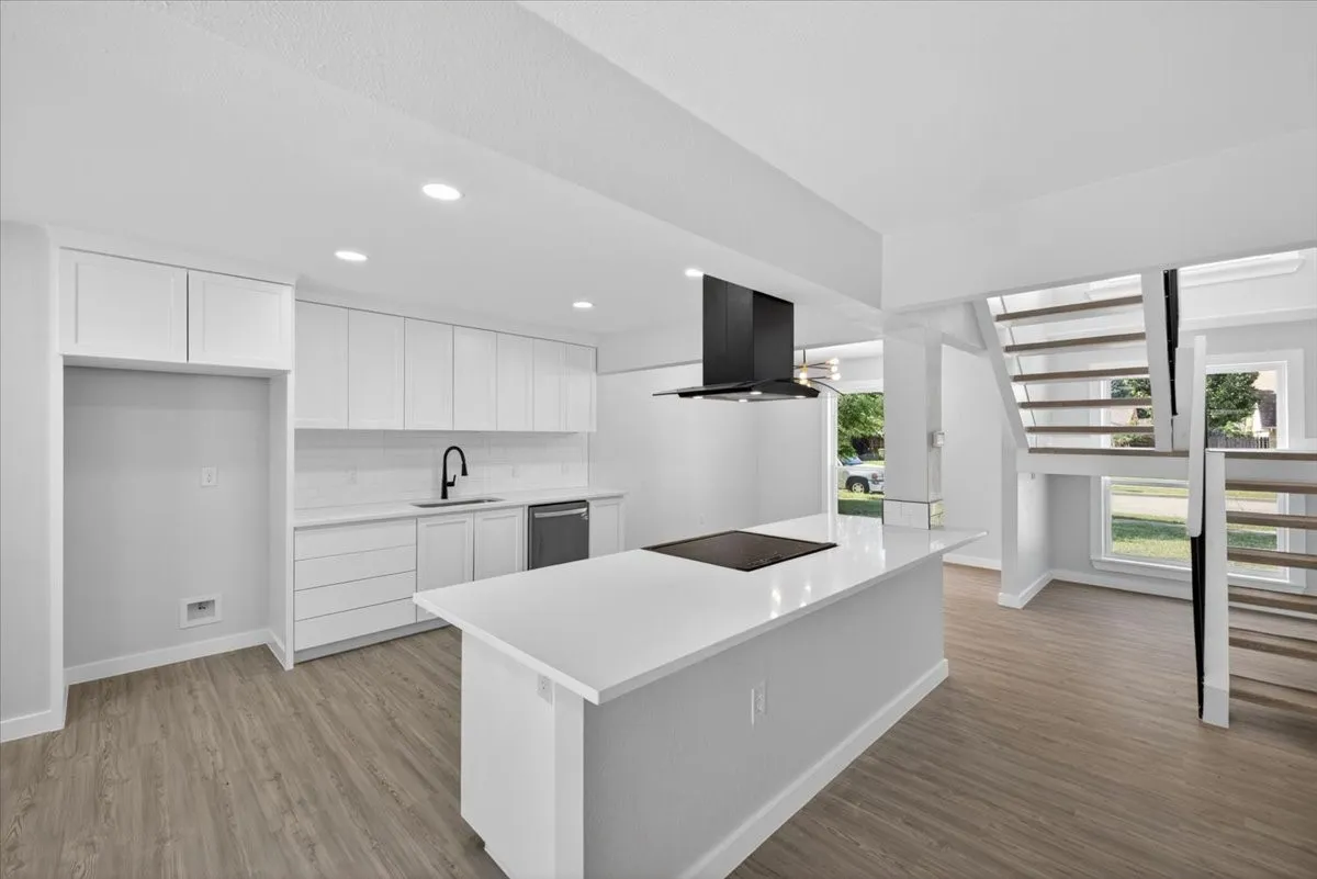 Contemporary kitchen featuring a center island with an integrated cooktop, white cabinetry, solid surface countertops, and a subway tile backsplash