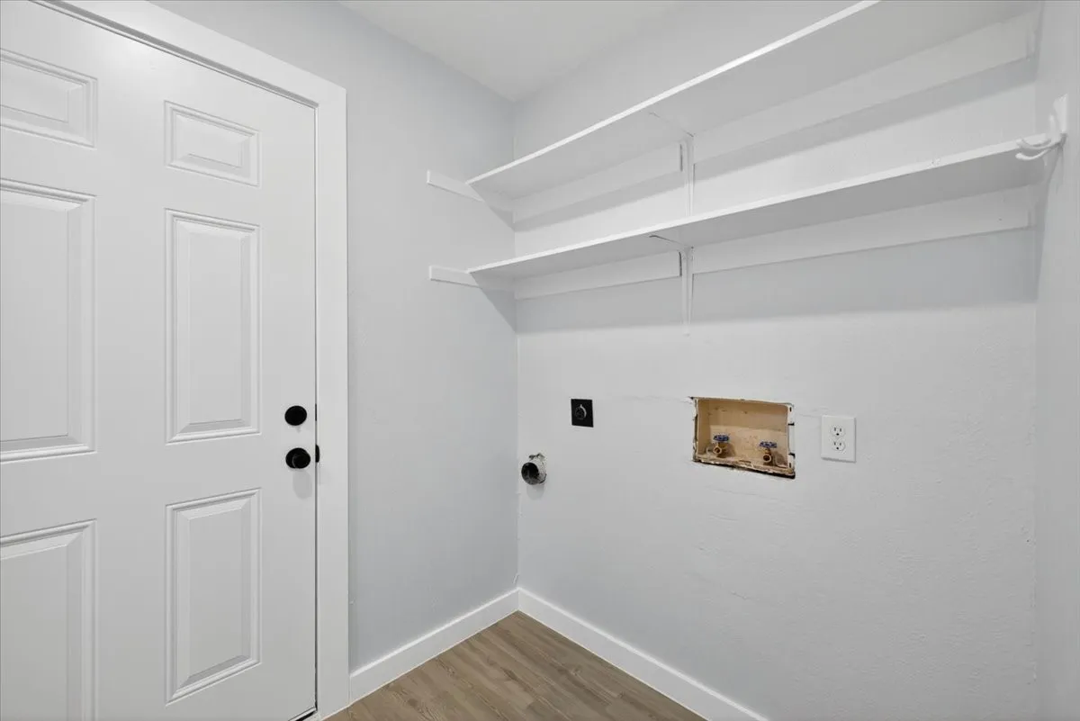 Dedicated utility space featuring light-toned walls, wood-finish flooring, and white trim
