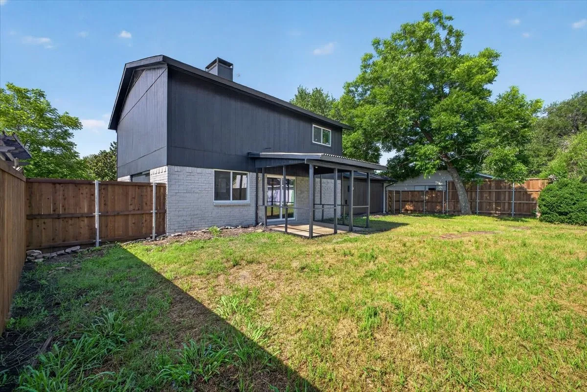 Expansive backyard featuring a covered patio, privacy fencing, and mature trees