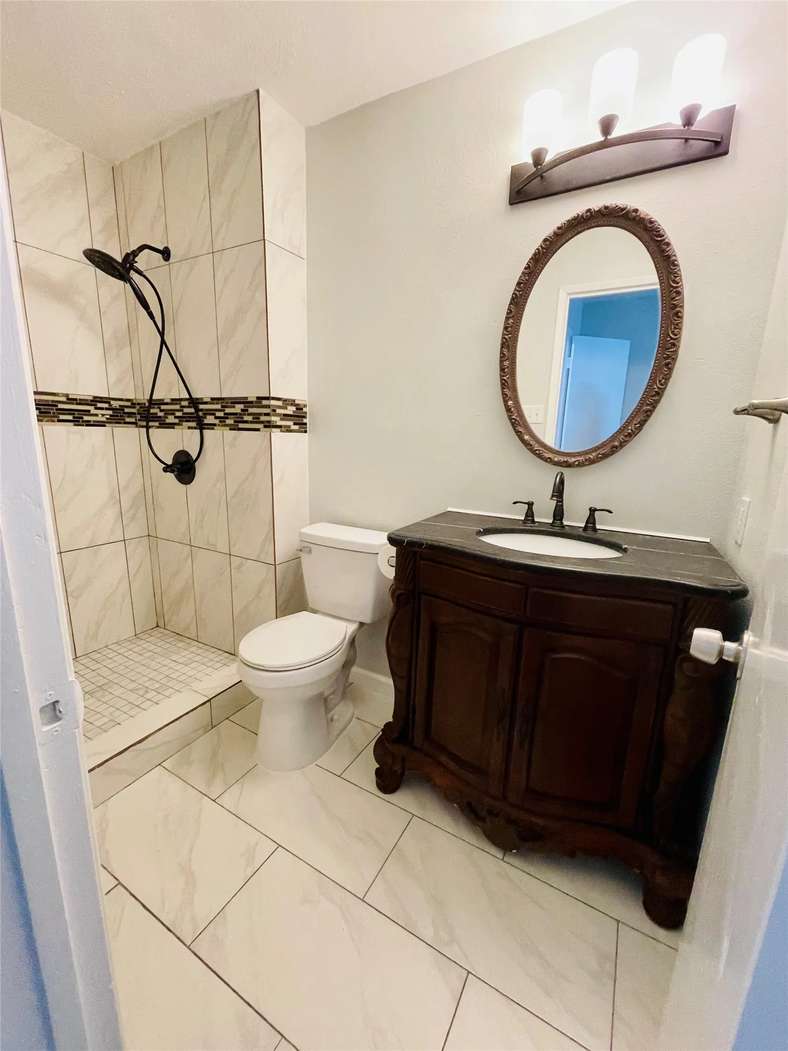 Bathroom featuring vanity, toilet, a tile shower, and tile patterned floors