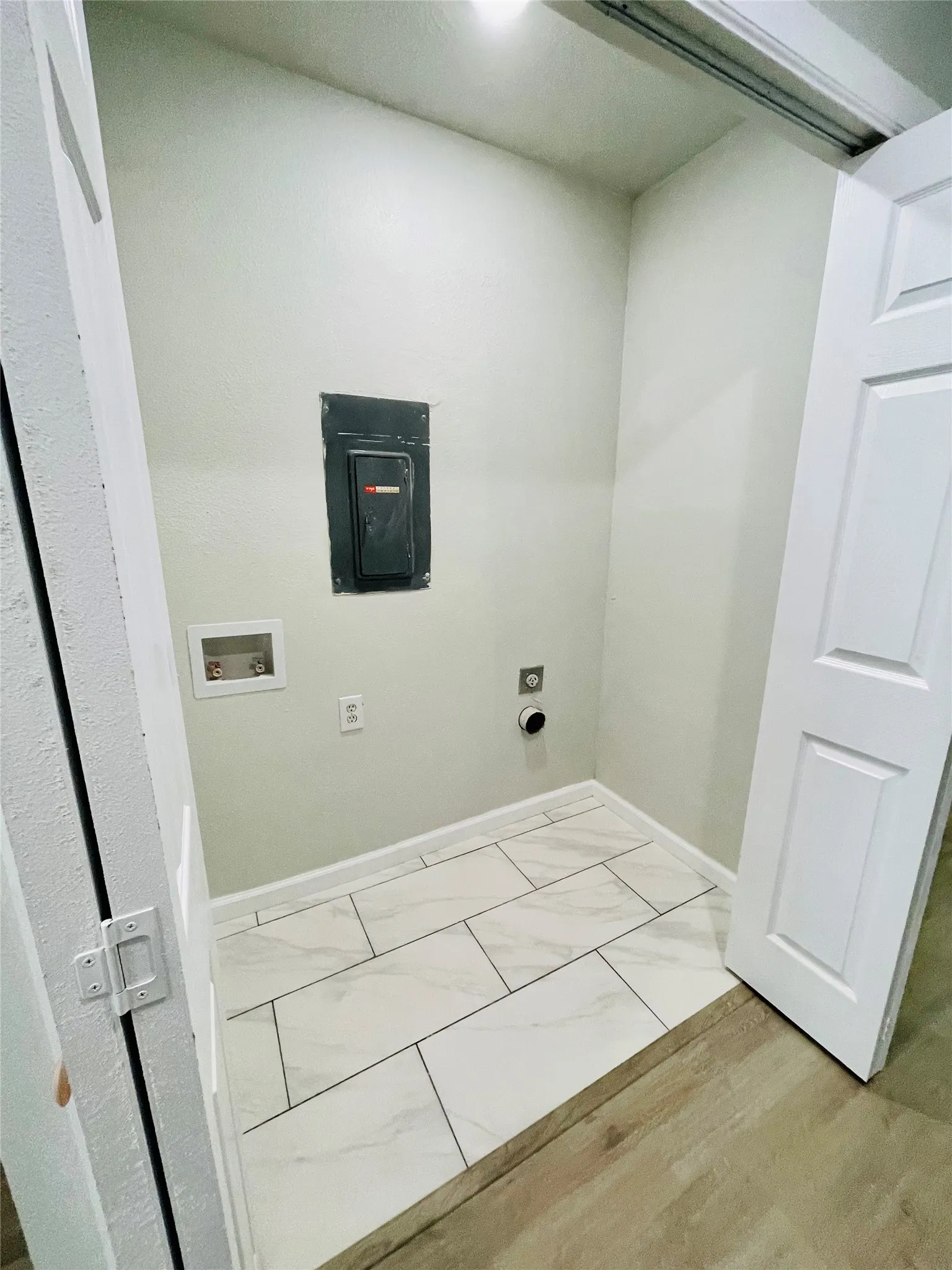 Washroom featuring hookup for a washing machine, electric panel, hookup for an electric dryer, and light hardwood / wood-style floors