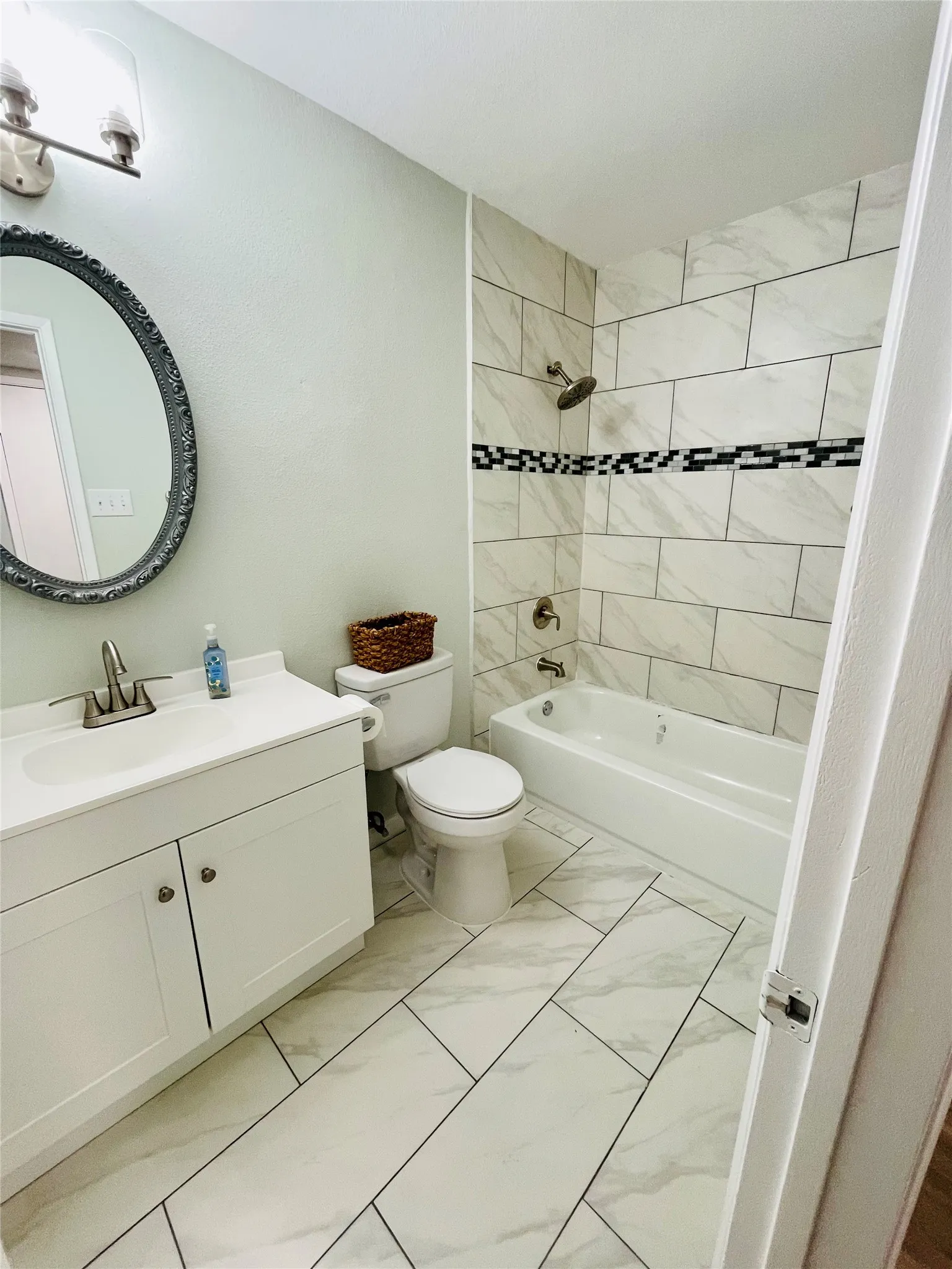 Full bathroom featuring tile patterned floors, toilet, tiled shower / bath combo, and vanity