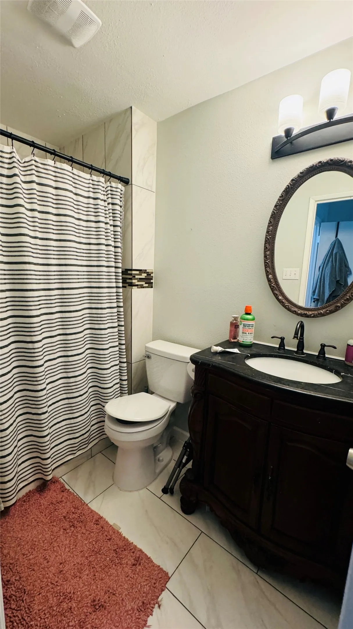Bathroom featuring tile patterned flooring, vanity, toilet, and a textured ceiling