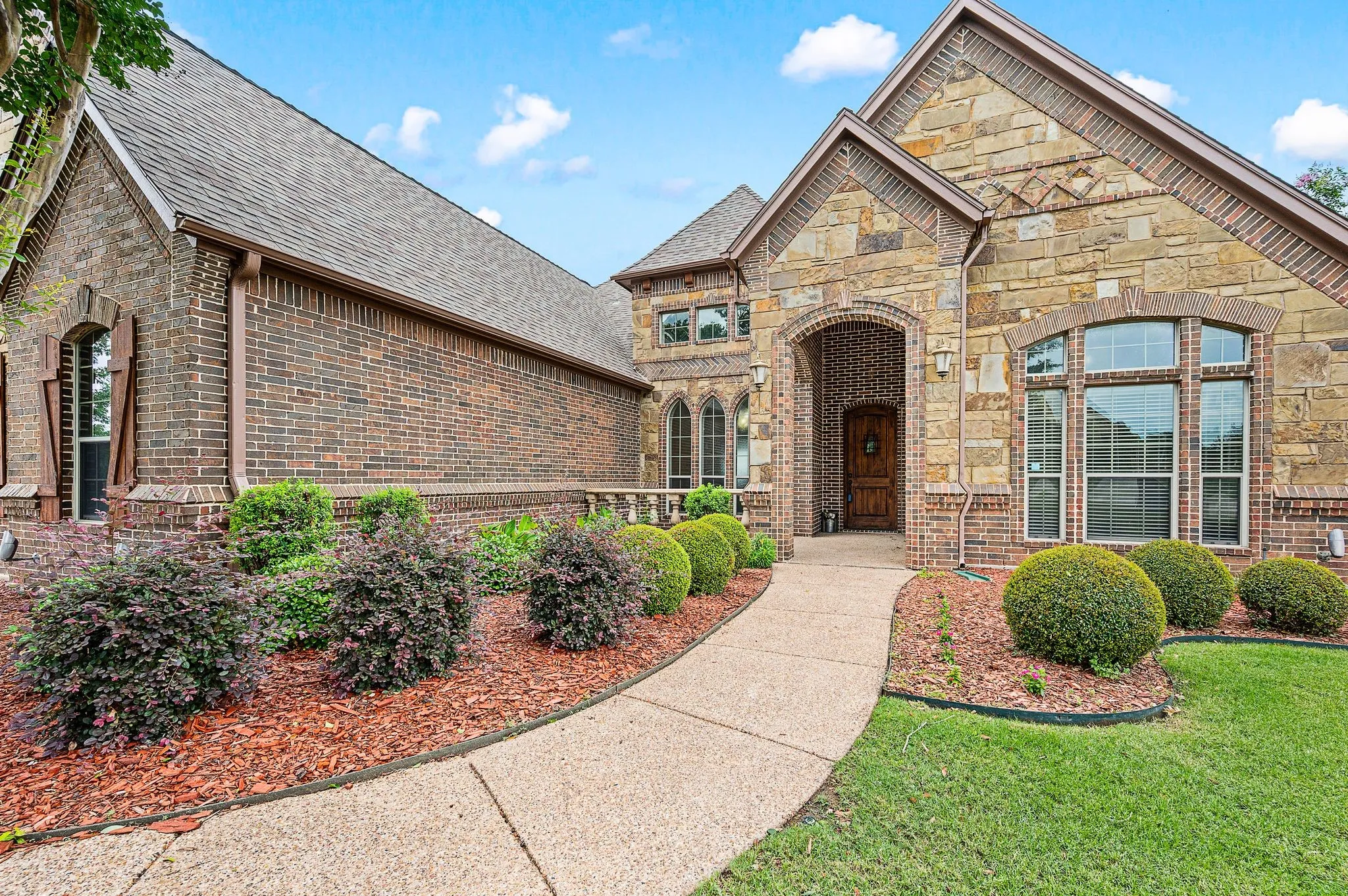 An aggregate walkway leads to the sunny front porch and covered portico. The 8ft front door is solid wood with a peek window.