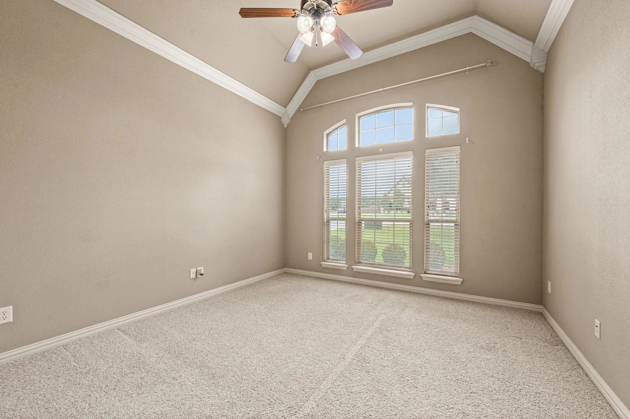 This second bedroom located downstairs has vaulted ceiling with crown molding, carpeted floor, ceiling fan and a walk in closet. Two inch blinds cover windows.