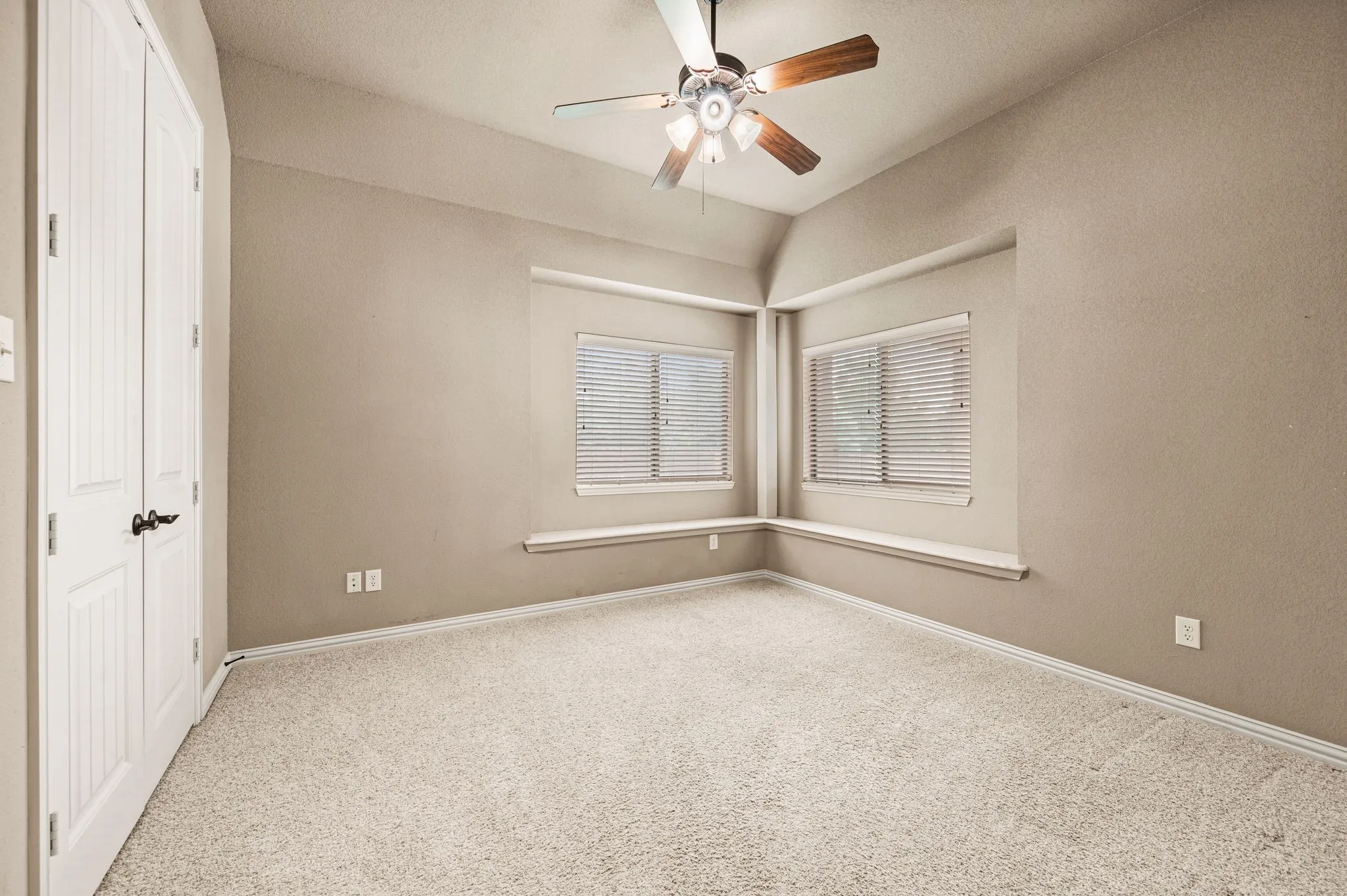 The fourth bedroom is also located downstairs and includes a wide double door closet, carpet flooring, ceiling fan, double windows with two inch blinds and vaulted ceiling.