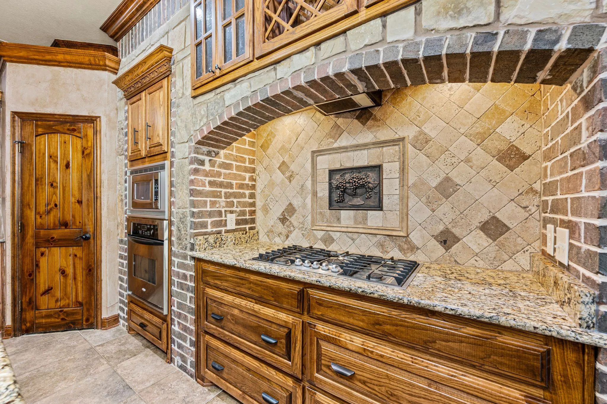 Stainless steel appliances include a 5 burner gas cook top with hidden vent hood, an electric oven and microwave. Tumbled stone backsplash. Hidden vent hood. Multiple drawers allow for easy access to pots and pans. Walk in pantry.