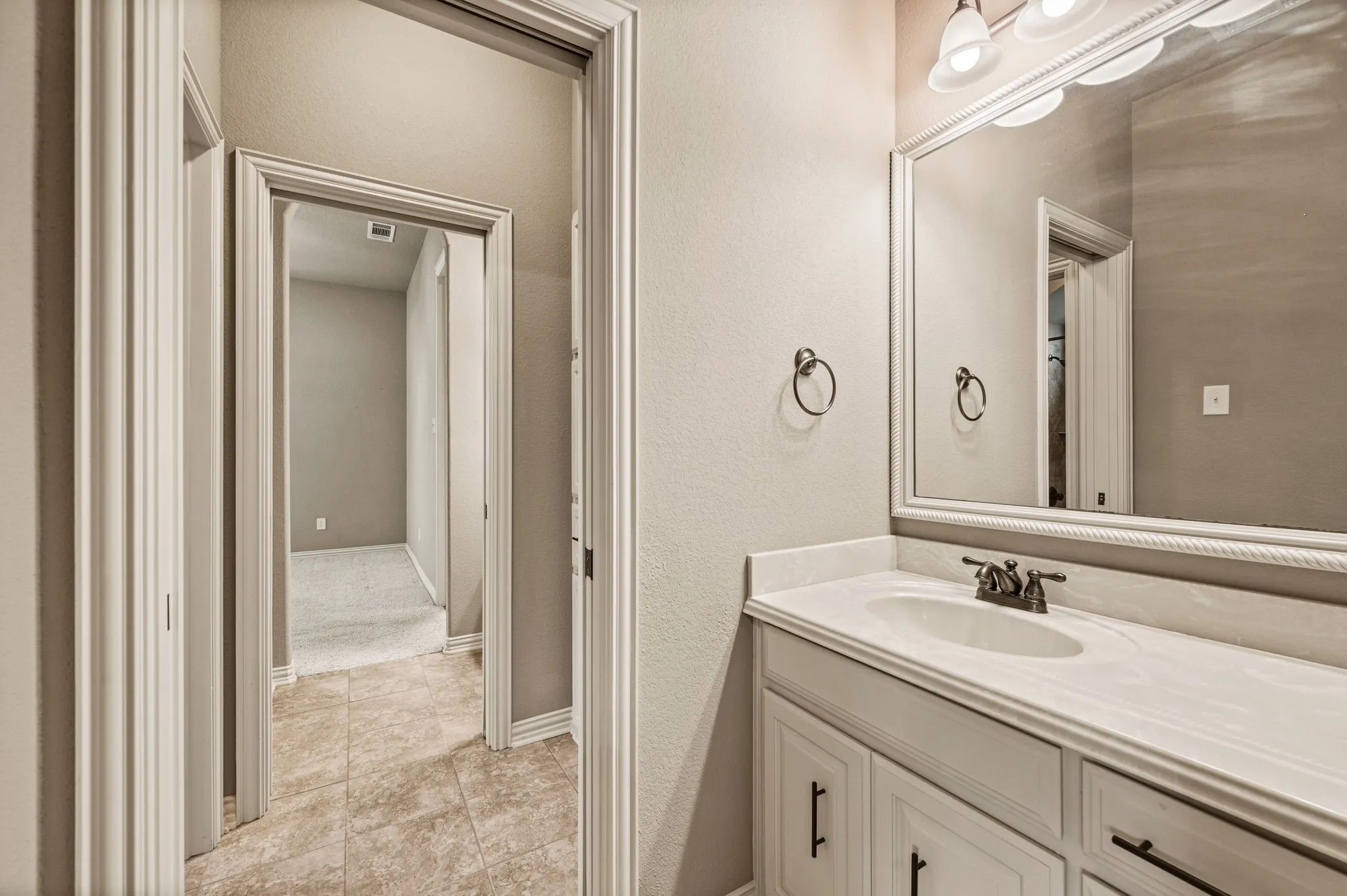 The Jack and Jill bathroom includes tile flooring, cultured marble vanity, framed mirror, and bronze fixtures and hardware.