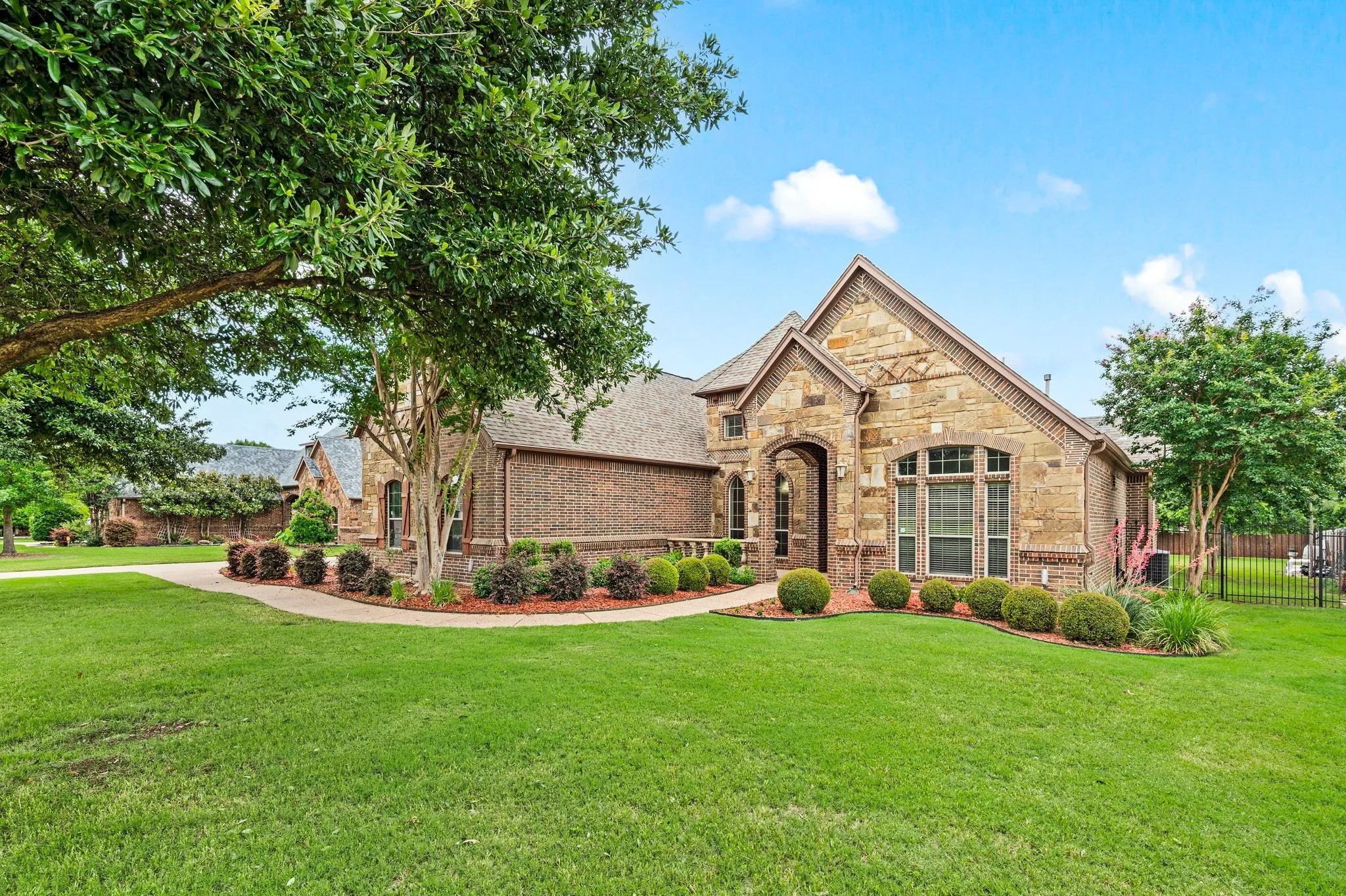 The home has full gutters and a manicured lawn with landscaping and trees.