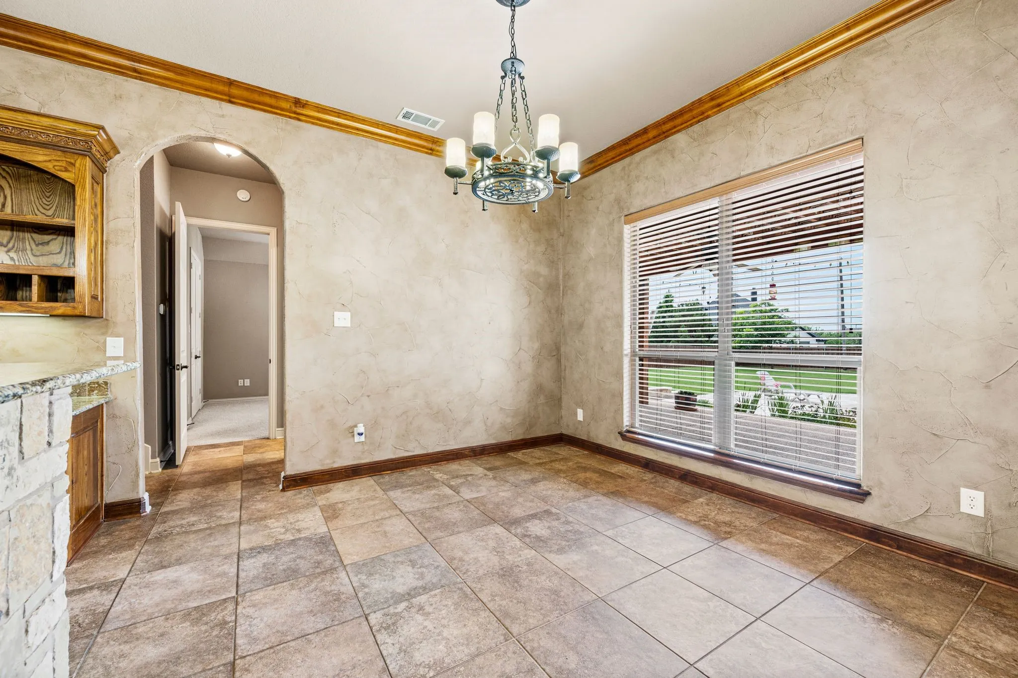 Spacious breakfast room with tile flooring and rustic chandelier. Hallway leads to secondary bedrooms.