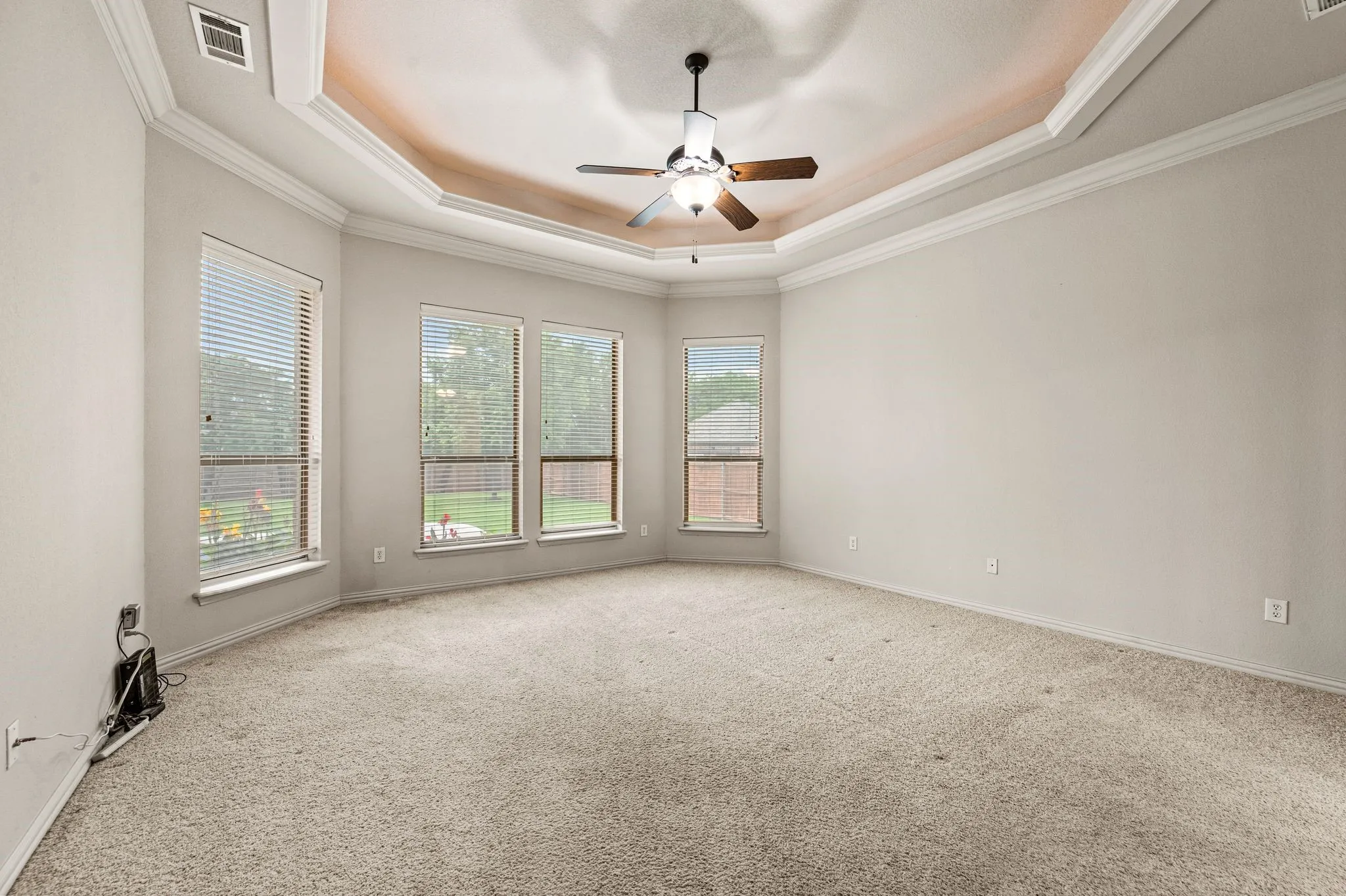 This spacious and private Primary bedroom is located downstairs. Soft lighting highlights the recessed ceiling.