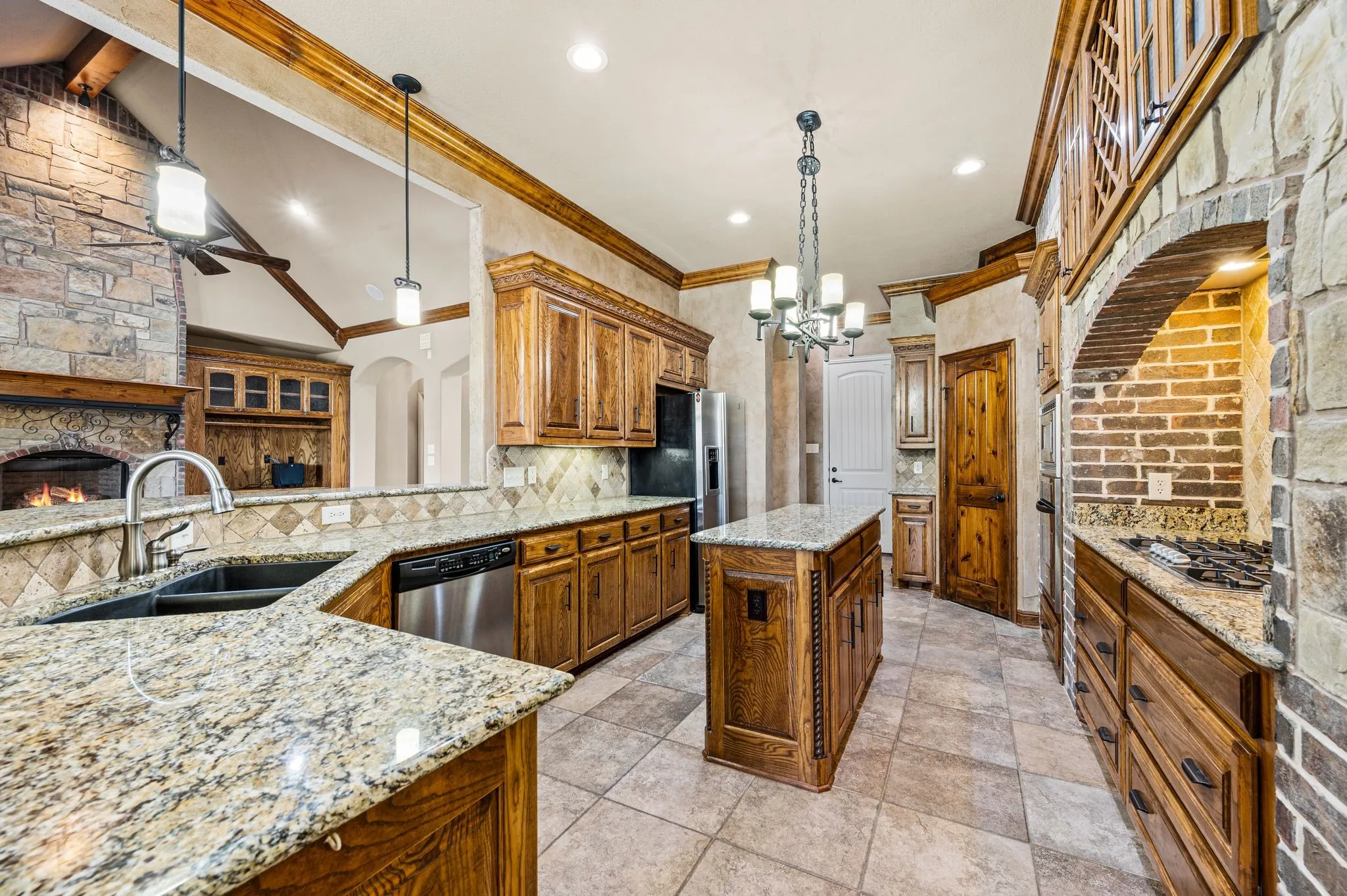 The kitchen includes both a breakfast bar and island. Granite countertops provide ample prep space. Deep updermount sink. Crown molding. Custom built cabinetry. Tile floors.