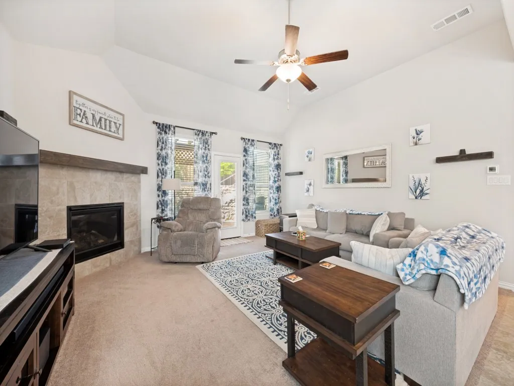 Living area featuring vaulted ceilings, a ceiling fan with integrated lighting, and carpet flooring