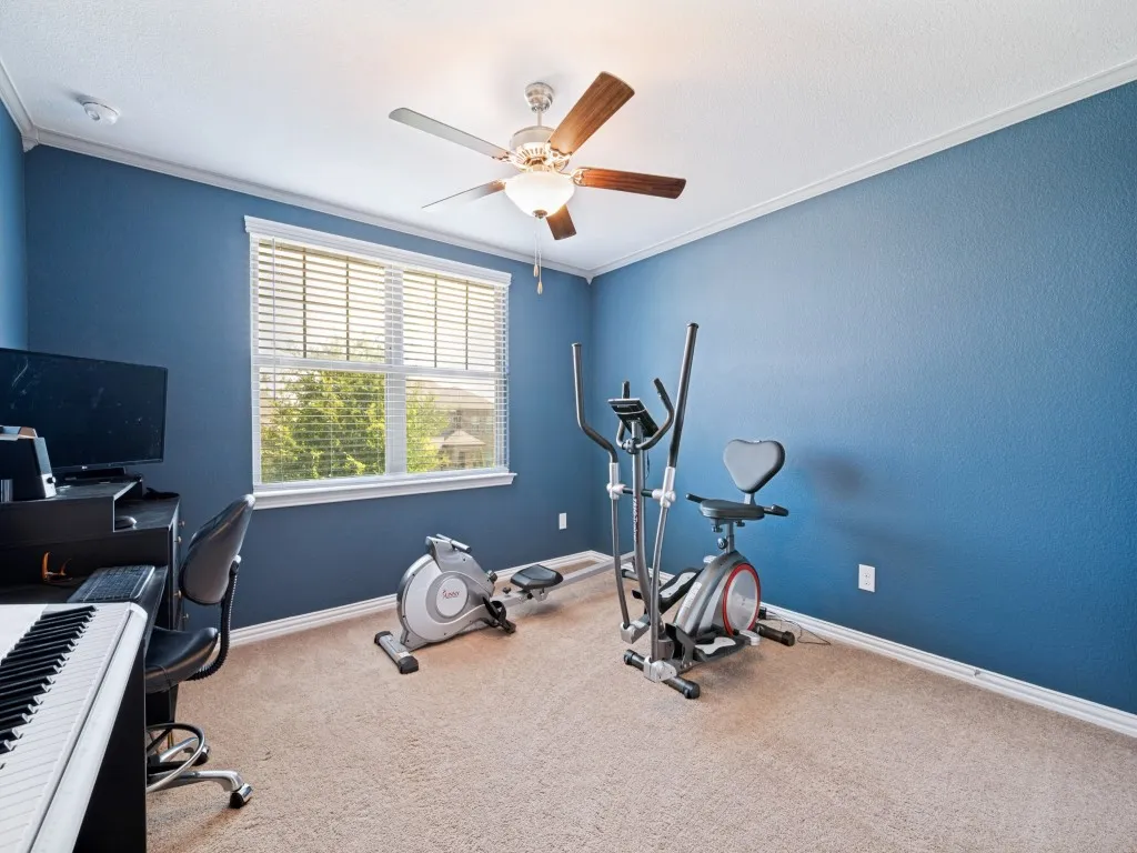 Interior room featuring blue wall finish, light-toned carpeting, a window with horizontal blinds, and a ceiling fan with integrated lighting