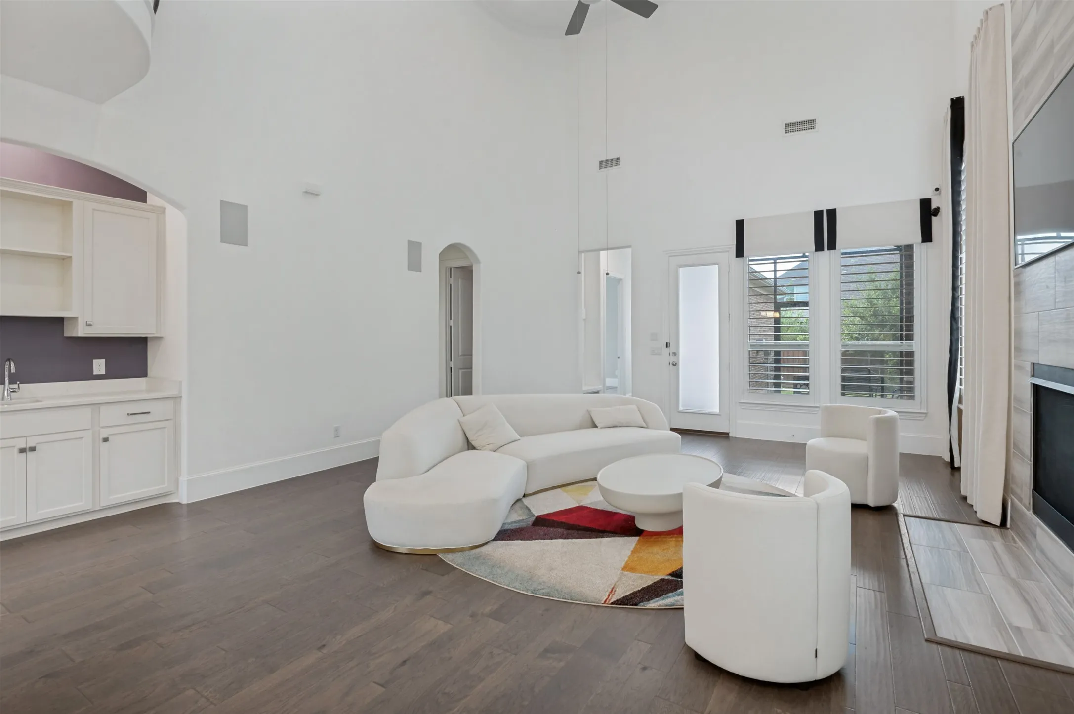 Spacious living area featuring high ceilings, wood-finish flooring, and built-in wall speakers