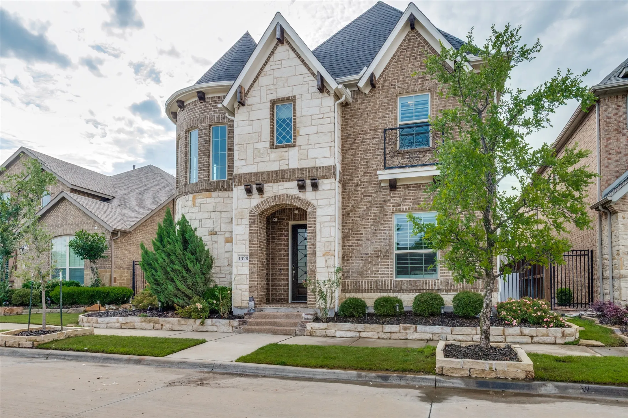 Distinguished brick and stone exterior with arched entry, gabled rooflines, and a turret feature