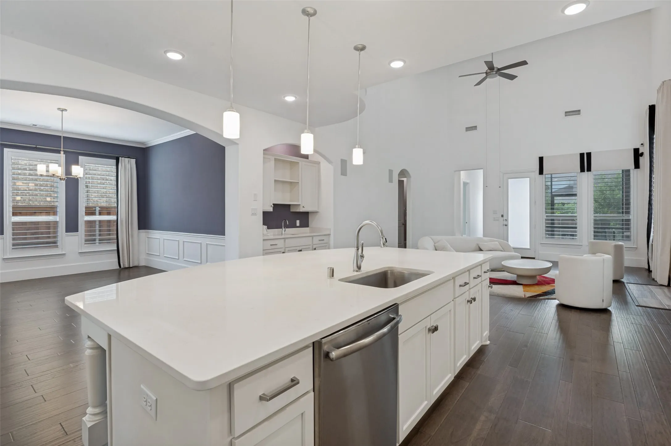 Spacious kitchen island featuring a white countertop, undermount sink, and stainless steel dishwasher