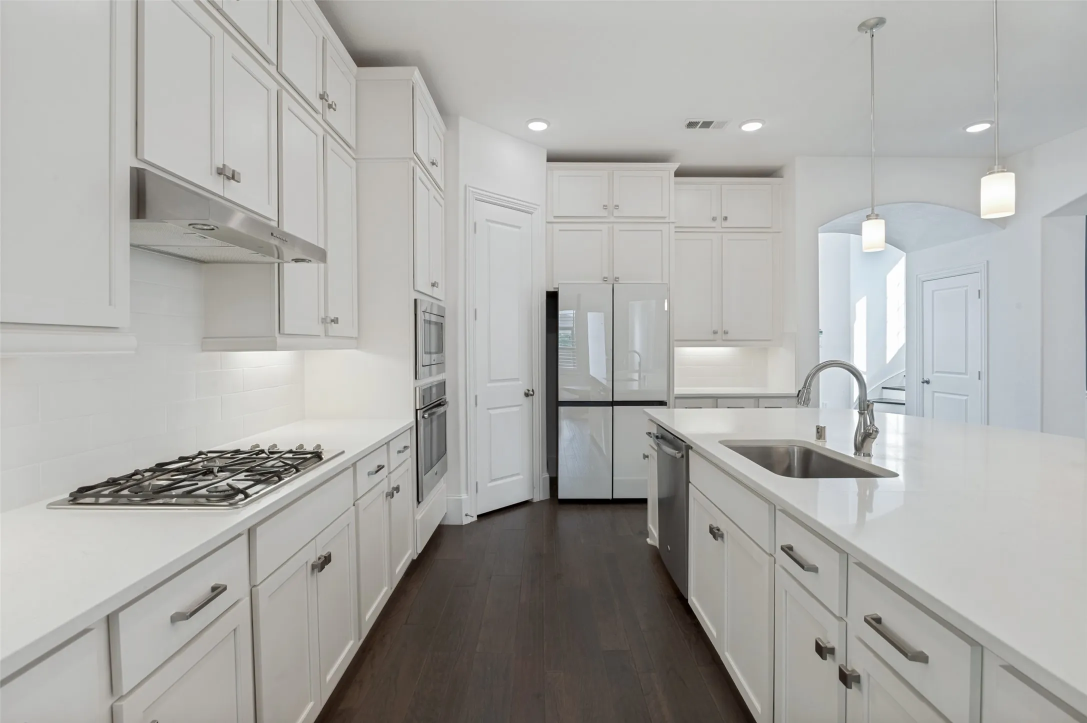 Contemporary kitchen featuring white cabinetry, dark wood-finish flooring, stainless steel appliances, a gas range, and an island with an undermount sink