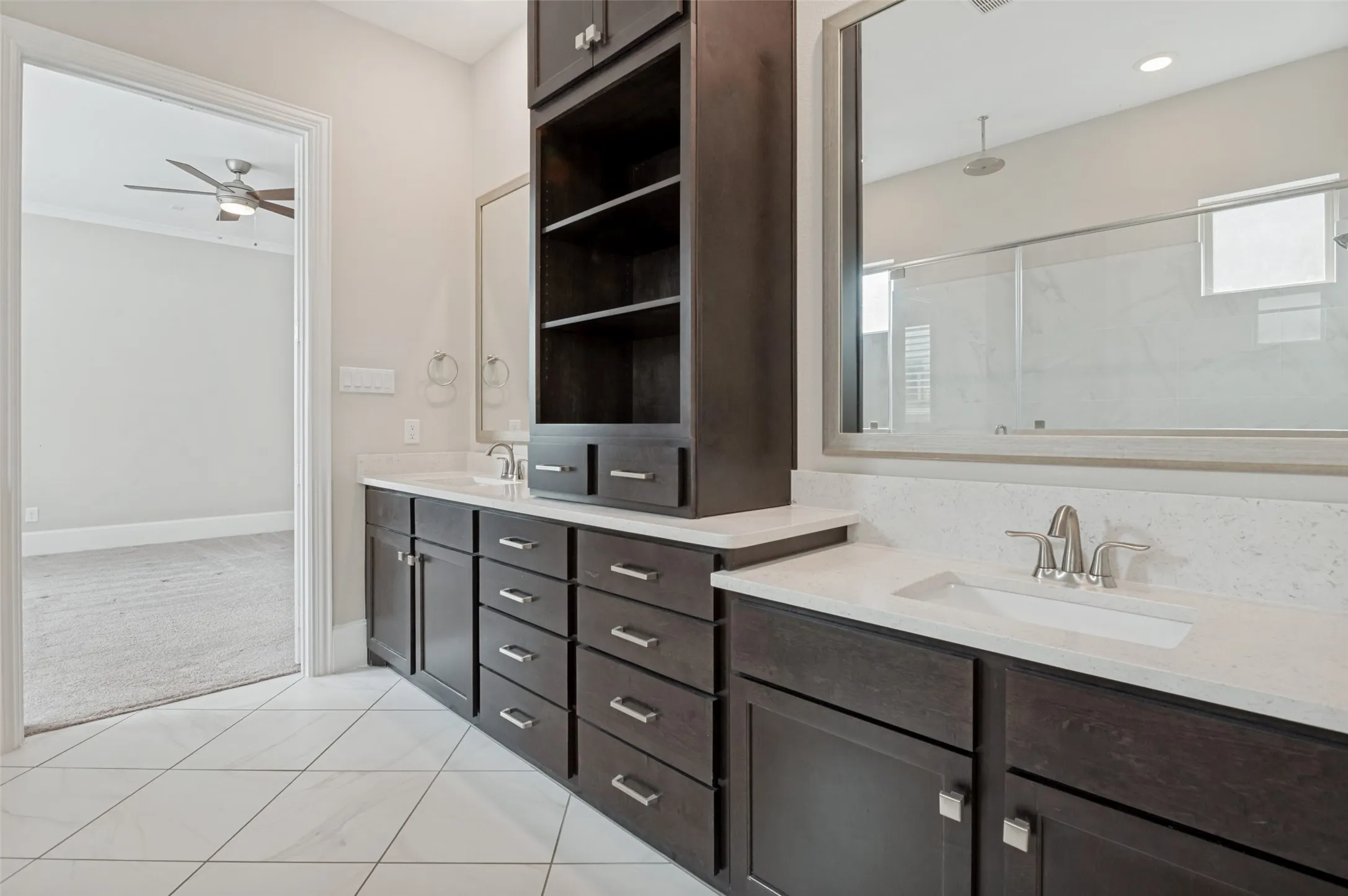 Bathroom vanity featuring dual under-mount sinks, white countertops, dark wood-finish cabinetry with silver hardware, and a large wall-mounted mirror