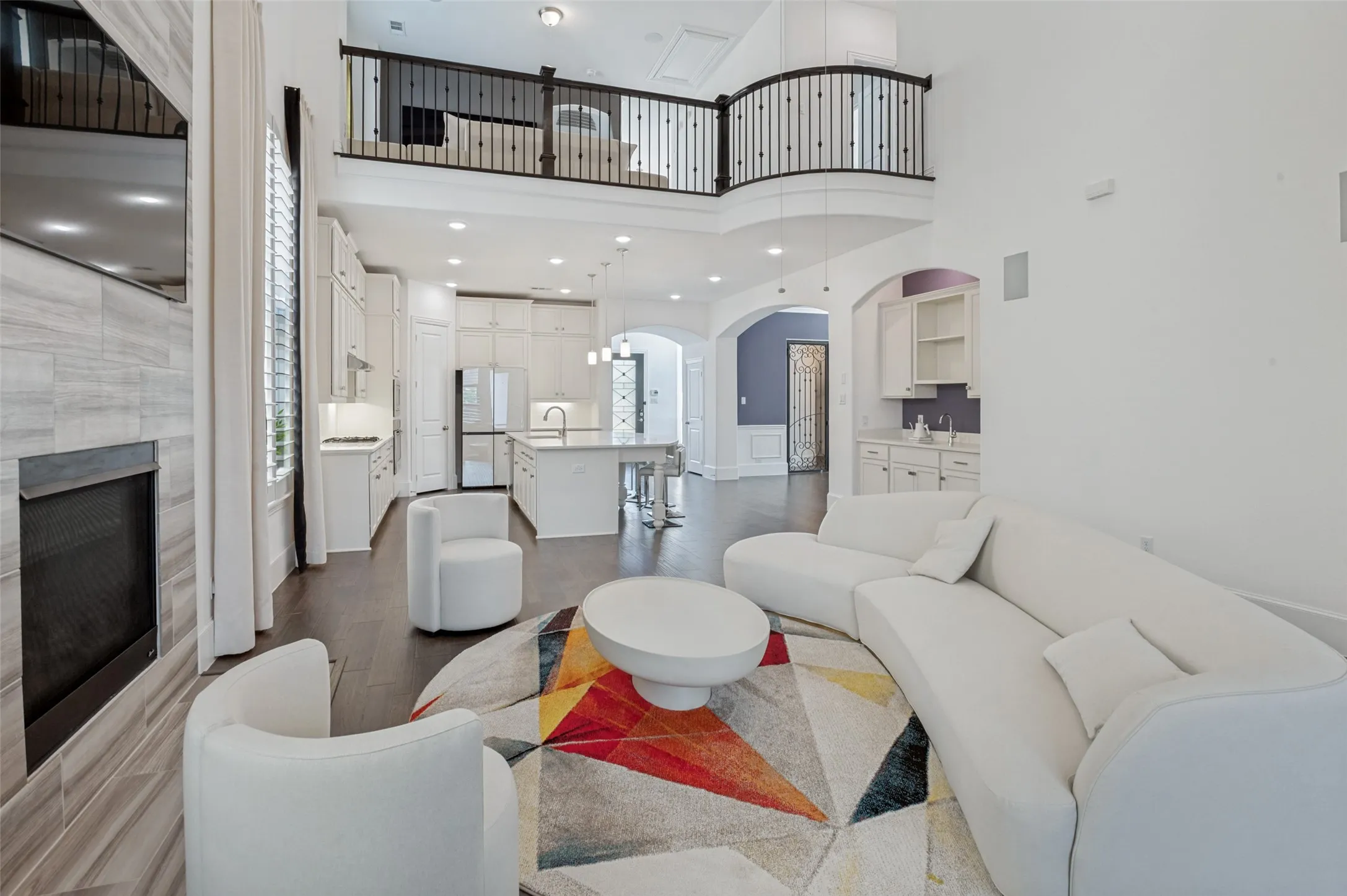 Open-concept living space featuring high ceilings, dark wood-finish flooring, and a stone-clad fireplace