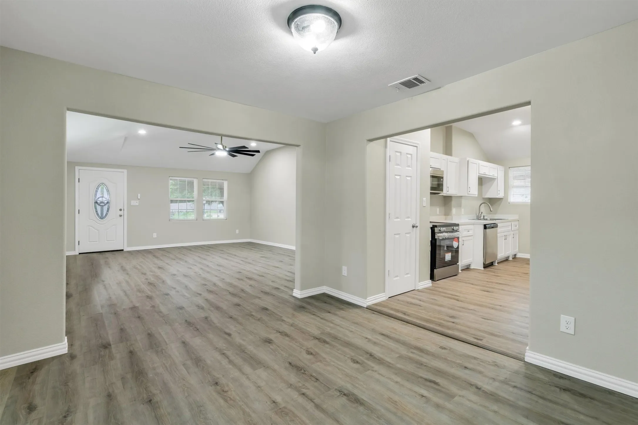 Open-concept living space featuring wood-finish flooring, a vaulted ceiling, and a ceiling fan