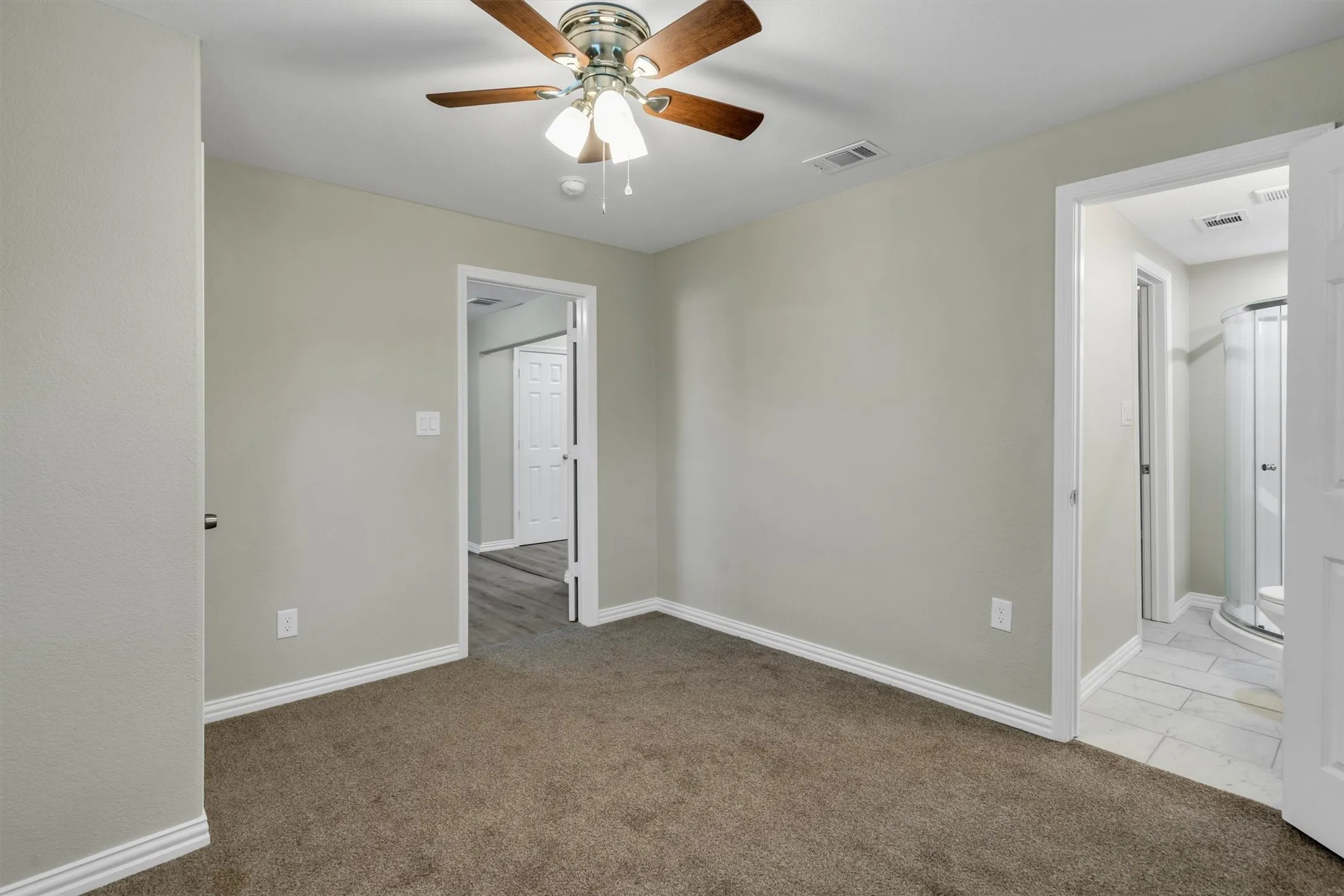 Room featuring neutral wall tones, brown carpeting, and a ceiling fan with integrated lighting