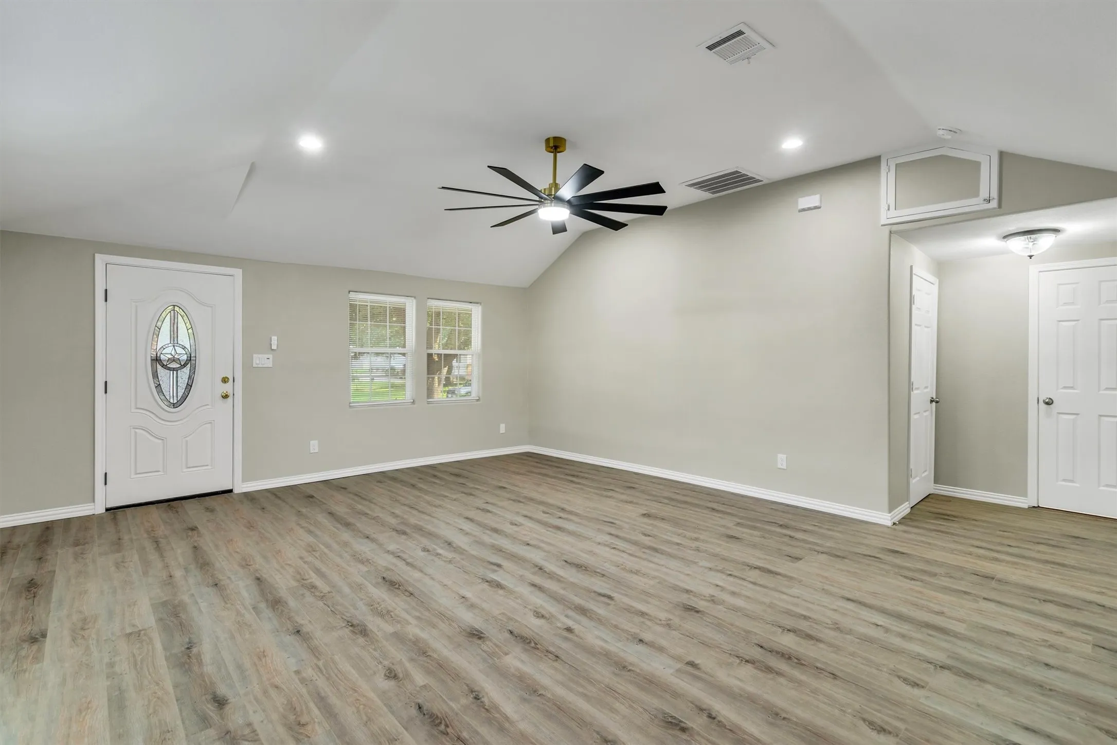 Spacious living area featuring wood-finish flooring, vaulted ceilings, and recessed lighting
