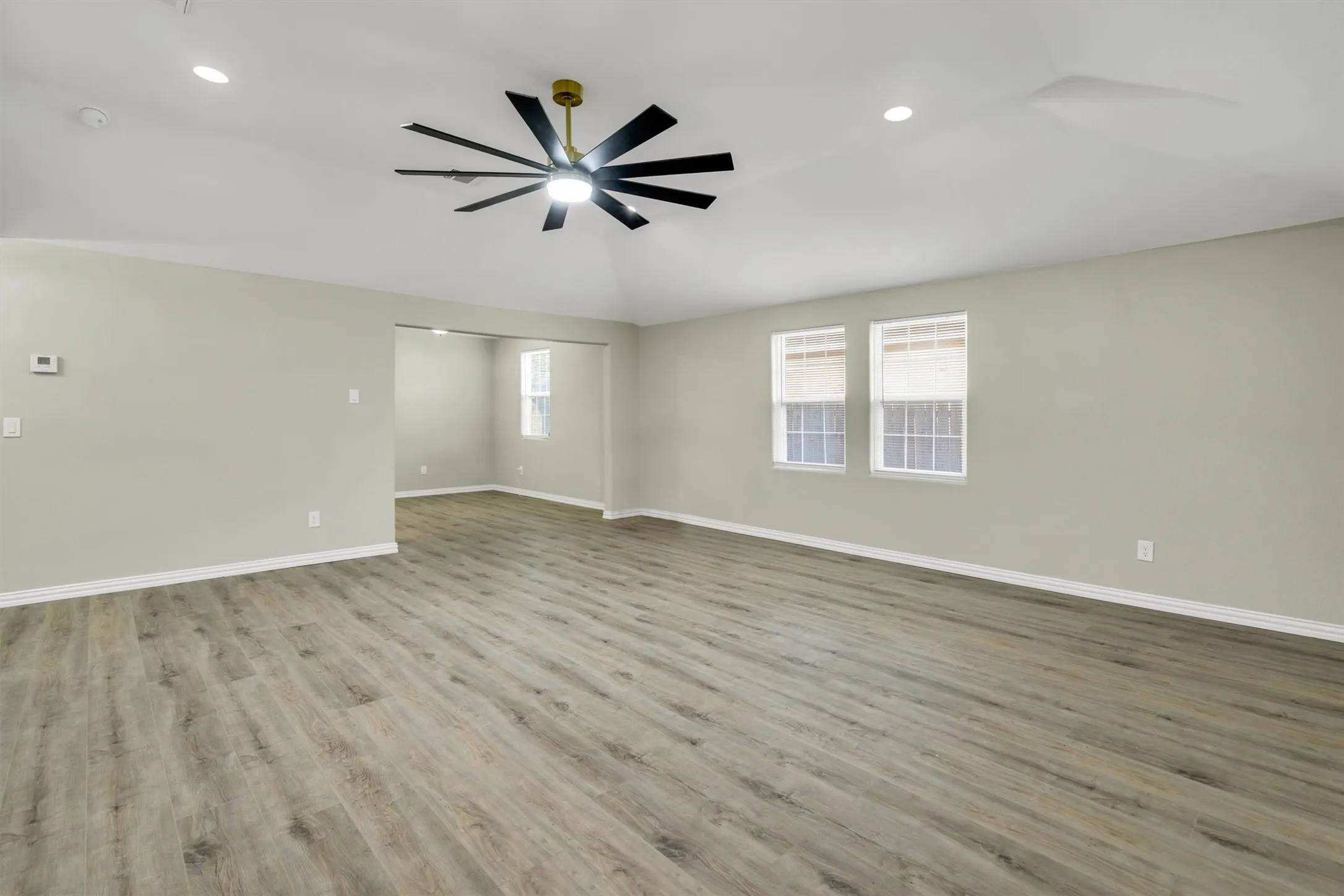 Expansive living area featuring wood-finish flooring, recessed lighting, and a modern ceiling fan