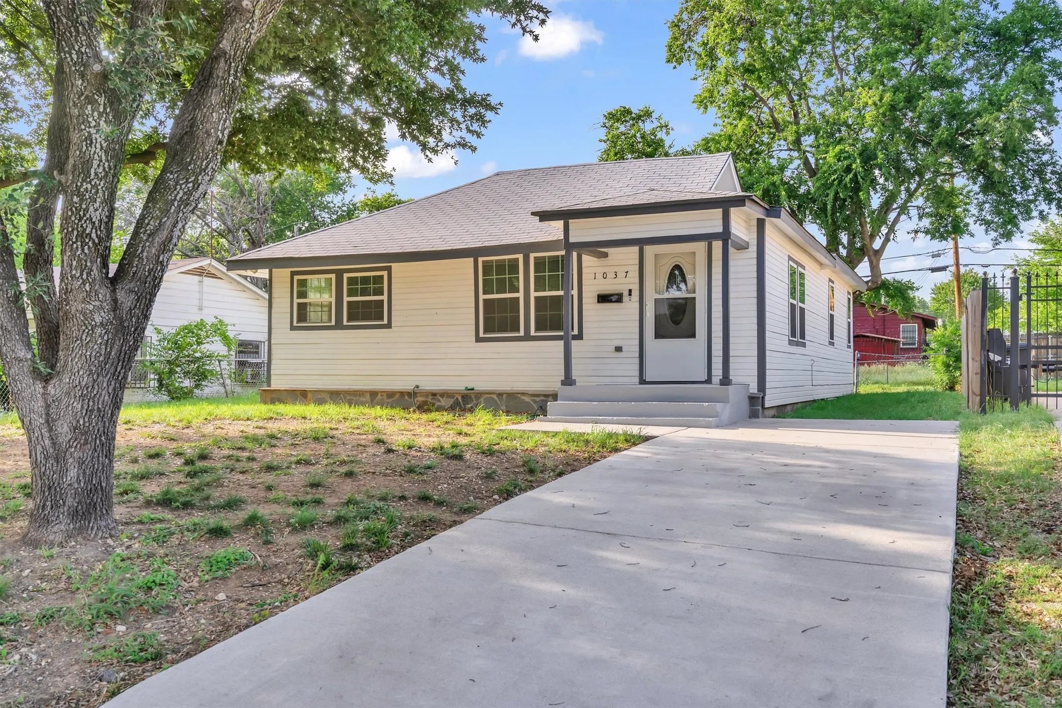 Single-story home featuring a covered front porch, white siding, dark trim windows, and a paved driveway