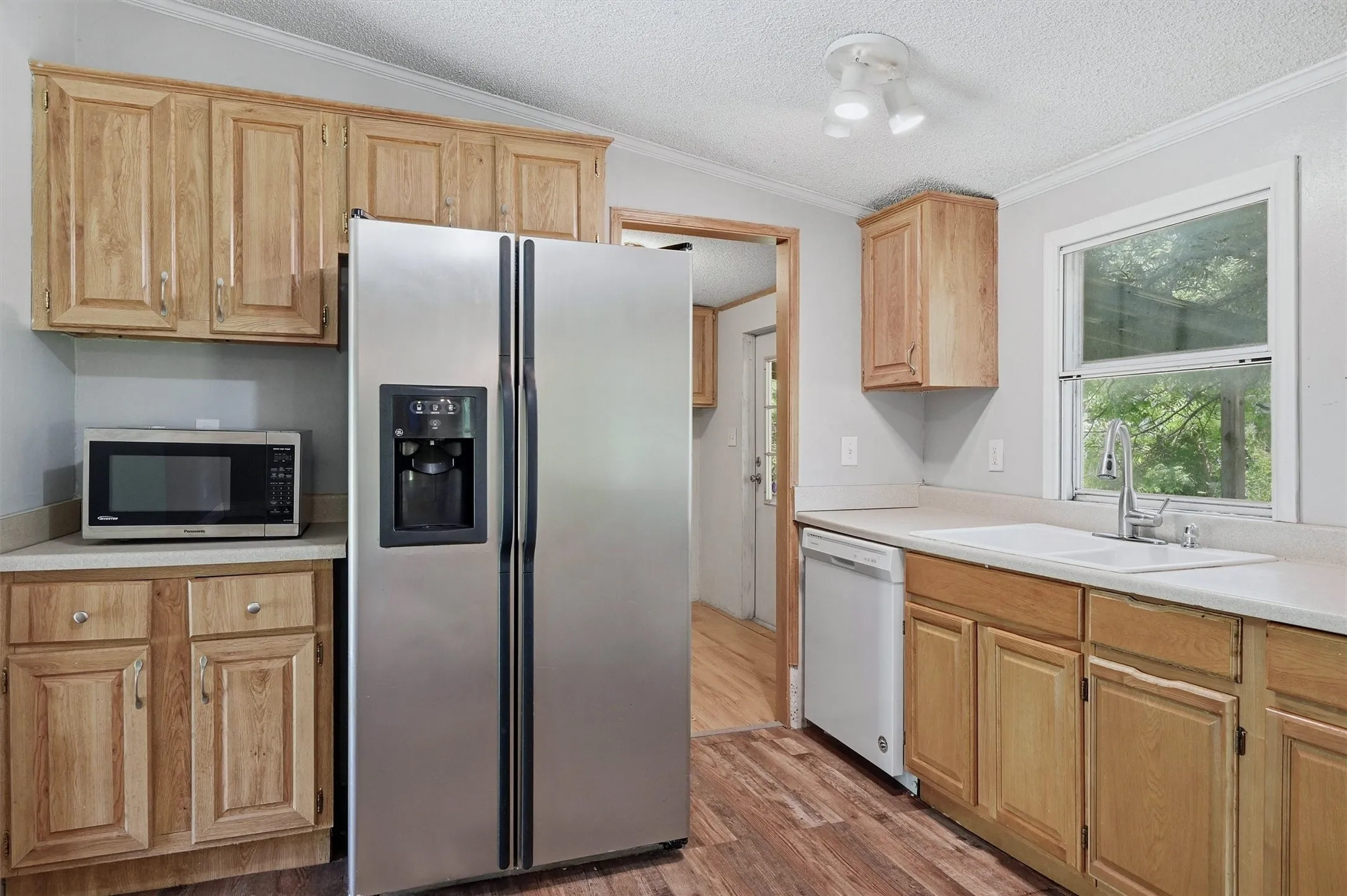 Kitchen featuring wood cabinetry, light-toned countertops, and wood-finish flooring