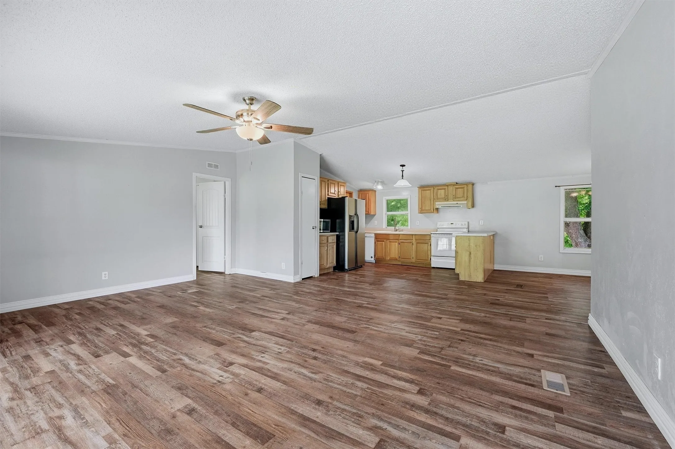 Expansive open-concept room featuring wood-finish flooring, light gray walls, and a ceiling fan