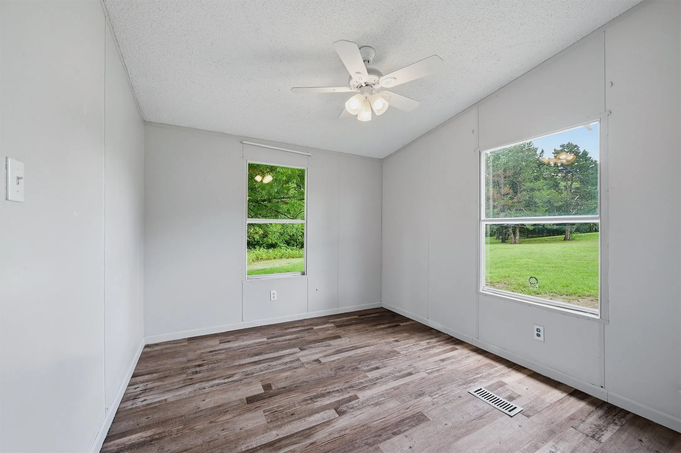 Room featuring wood-finish flooring, light gray walls, and a white ceiling fan with integrated lighting