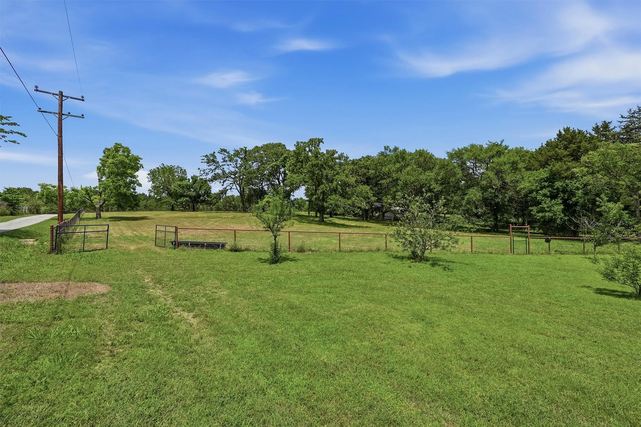 Expansive green space featuring perimeter fencing and a treeline backdrop