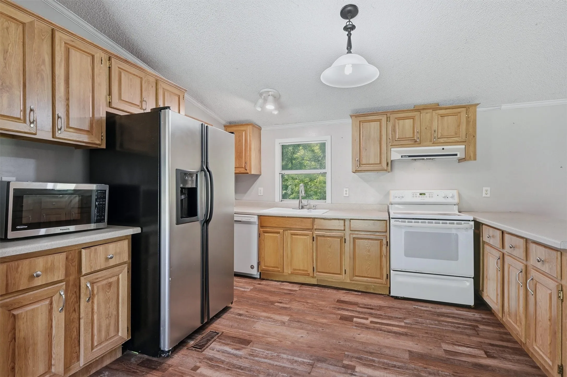 Kitchen featuring wood-finish flooring, oak cabinetry, light-toned countertops, and a double-basin sink