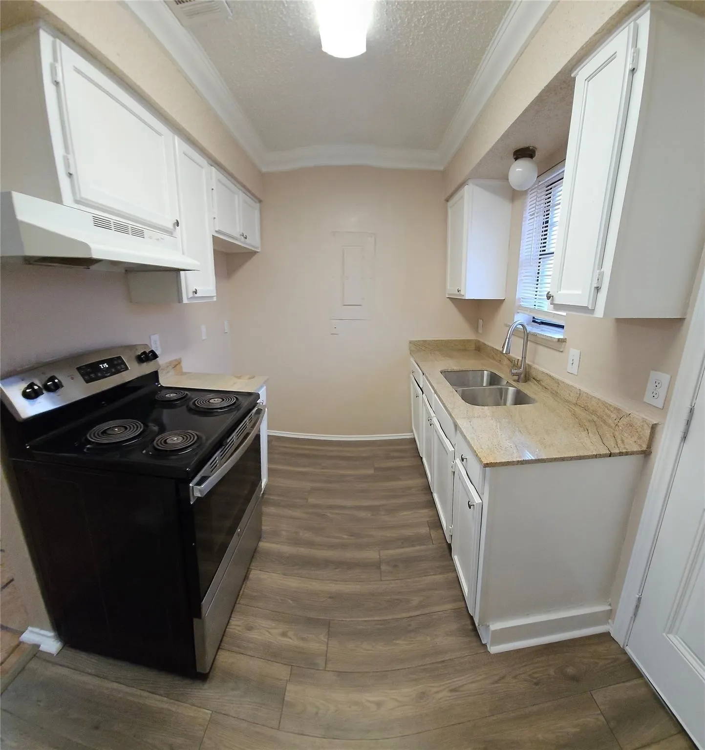 Galley kitchen featuring wood-finish flooring, white cabinetry, and natural stone countertops