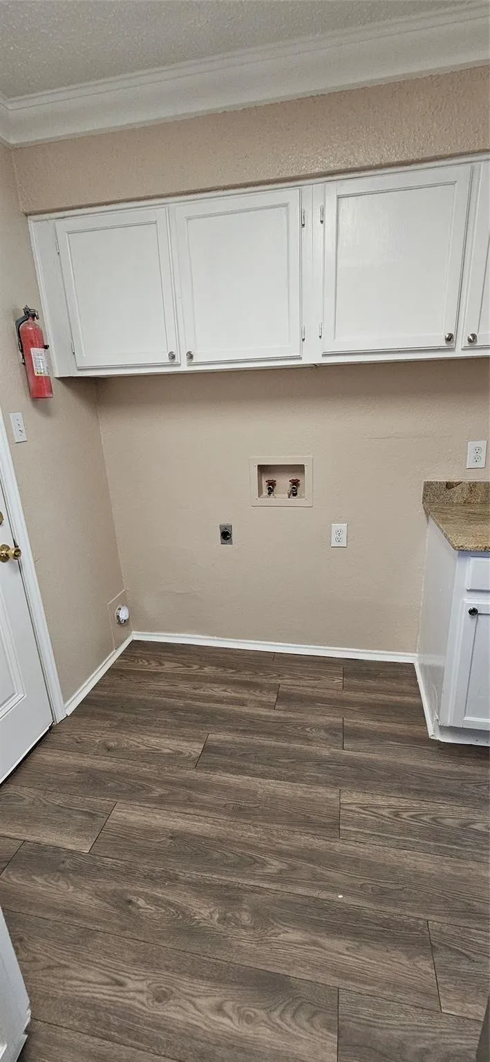 Dedicated utility space featuring wood-finish flooring, white cabinetry, and crown molding