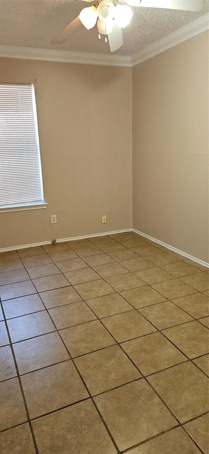 Spacious room featuring neutral tone walls, tile flooring, a ceiling fan with integrated lighting, a window with horizontal blinds, and white baseboards