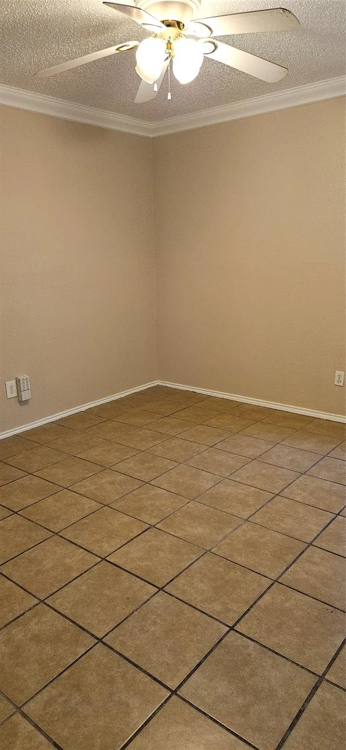 Neutral-toned tile flooring complemented by a ceiling fan with integrated lighting